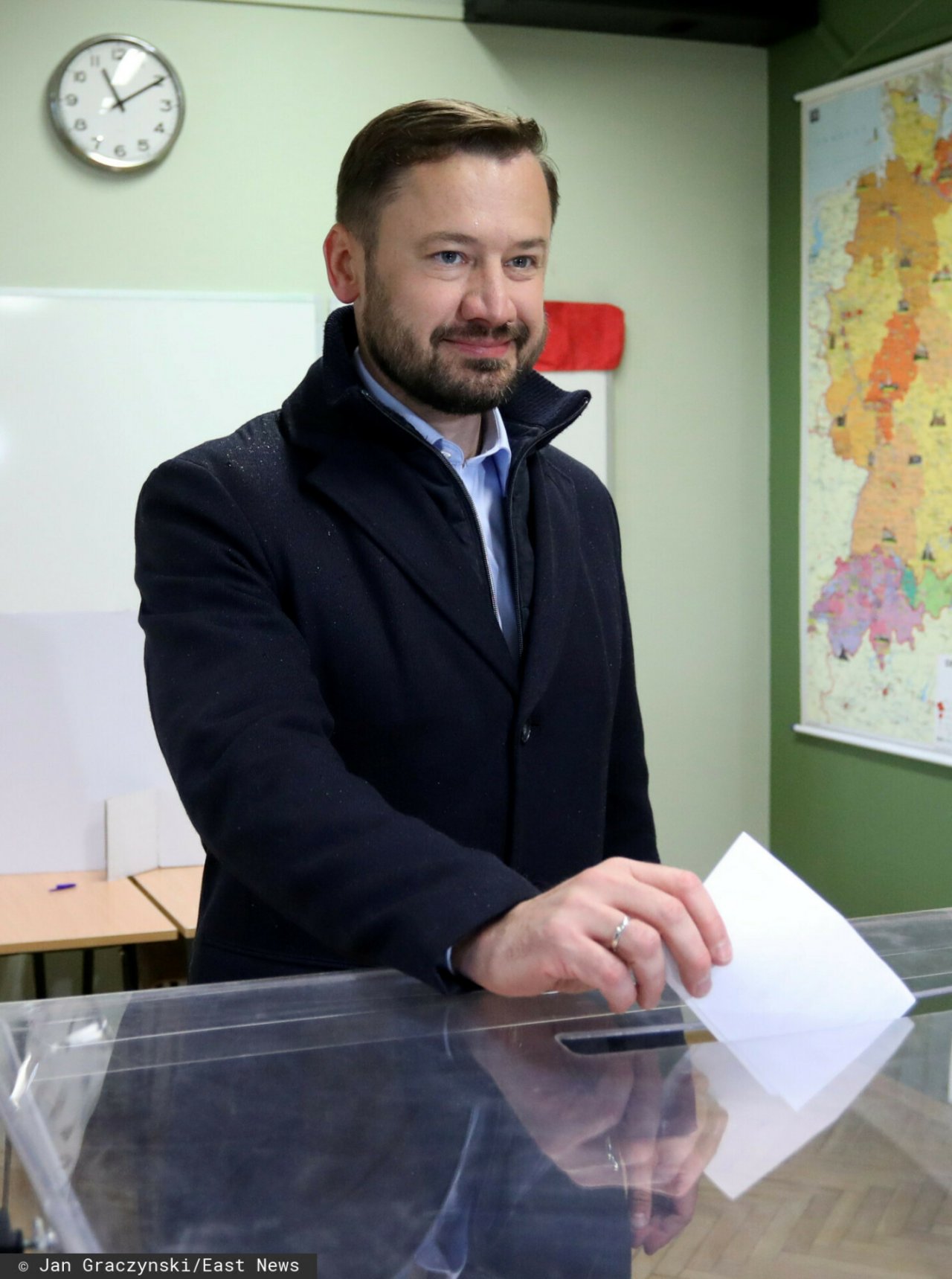 Aleksander Miszalski uśmiechnięty w granatowym płaszczu
