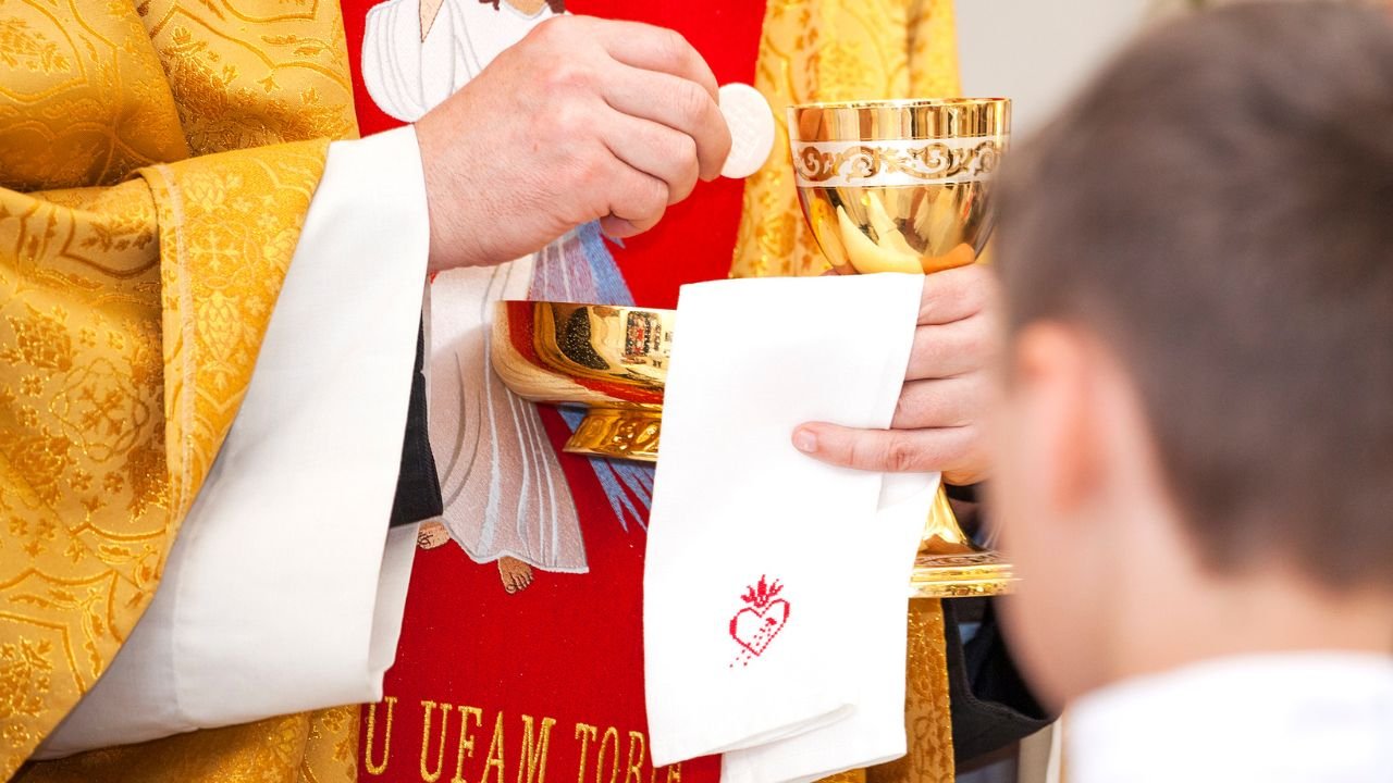 ksiądz rozdziela komunię