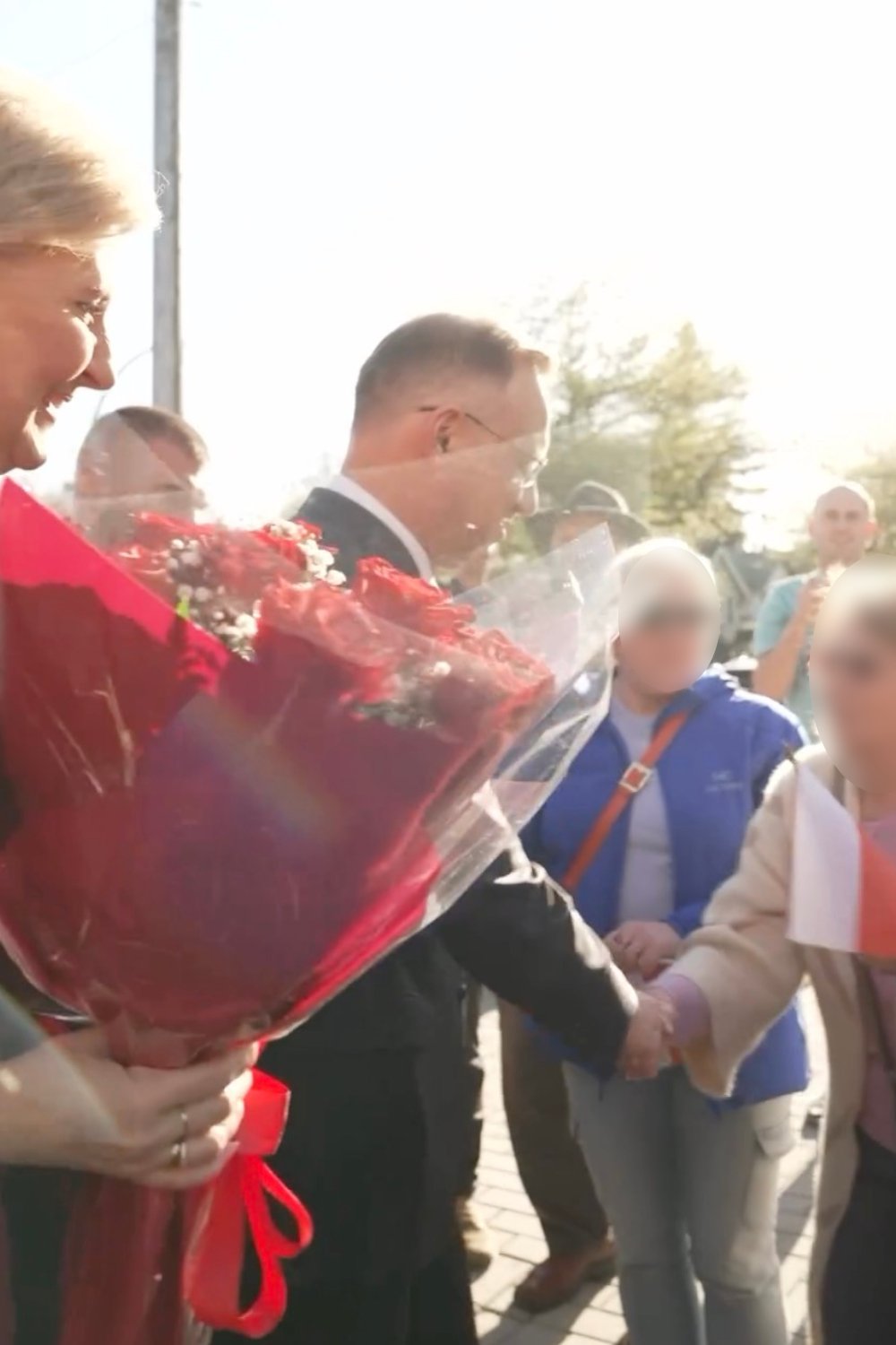 Andrzej Duda podający dłoń kobiecie ubranej w białą kurtkę 