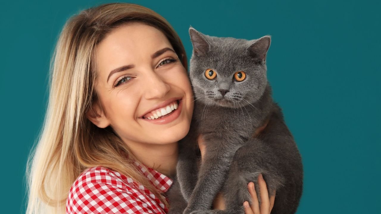 Kobieta blondynka z kotem na rękach uśmiecha się do kamery