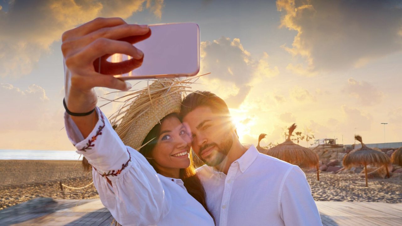 Kobieta i mężczyzna robią selfie przy zachodzie słońca na plaży