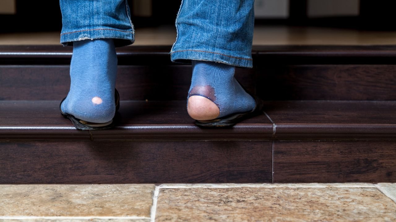 mężczyzna w niebieskich jeansach z niebieskimi skarpetkami na nogach  dziurawymi