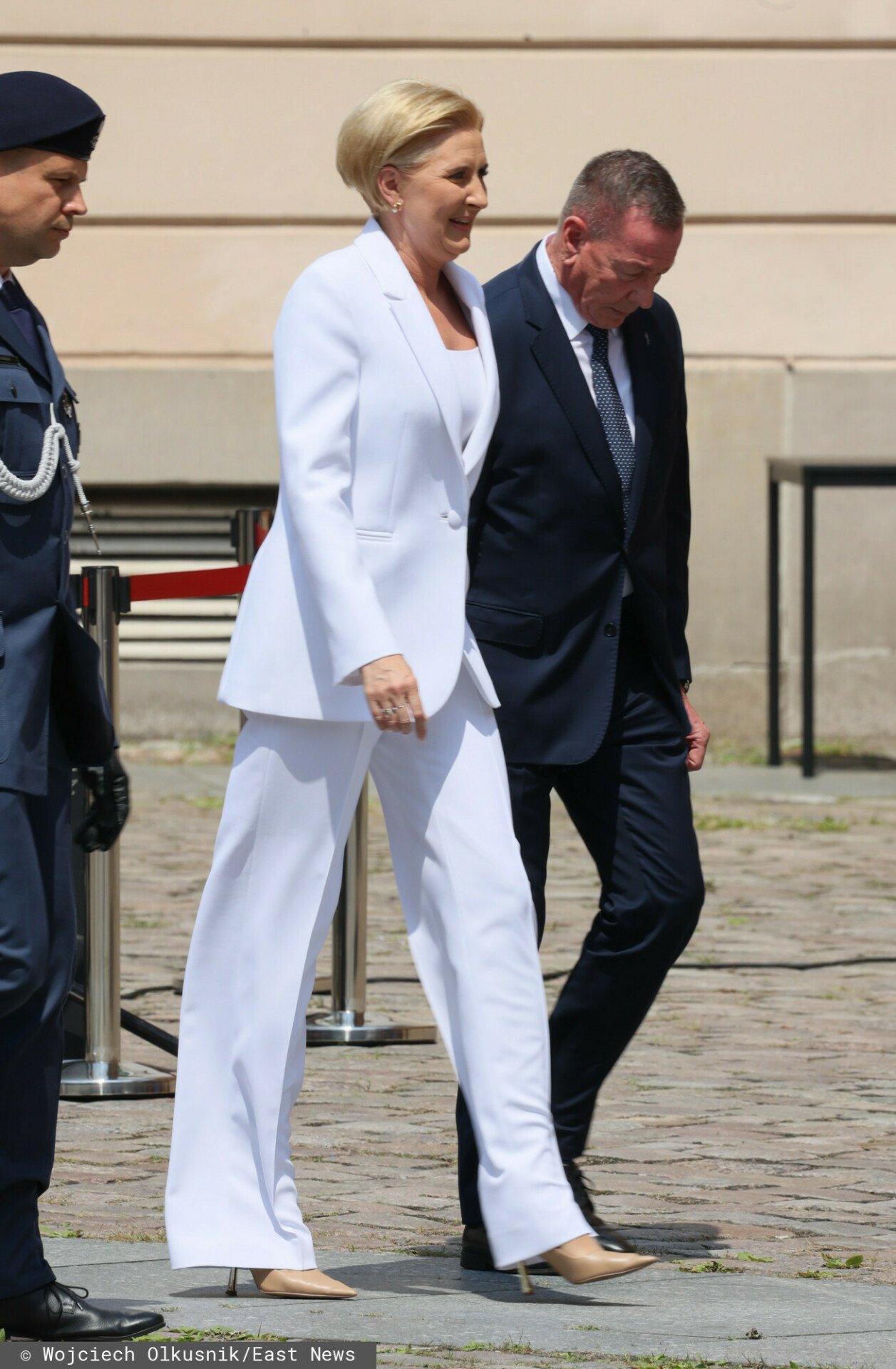 Agata Duda w białym komplecie idzie ulicą