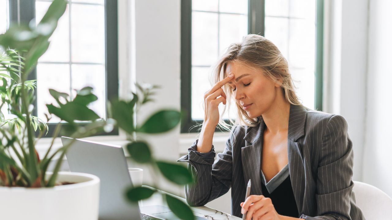 smutna kobieta siedzi przy biurku z laptopem