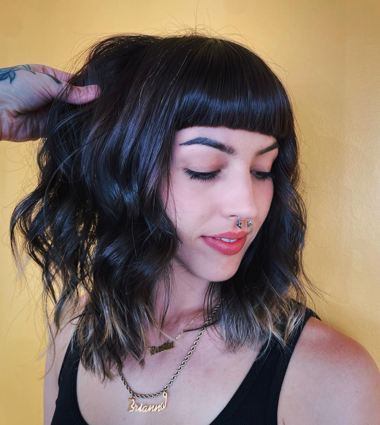 Zbliżenie na brunetkę w long bobie i w grzywce blunt bangs.