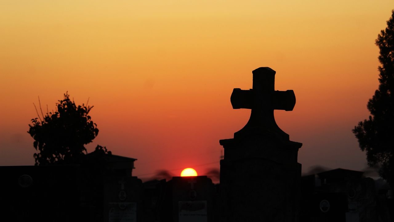 Widok ciemnego krzyża na tle zachodzącego słońca.