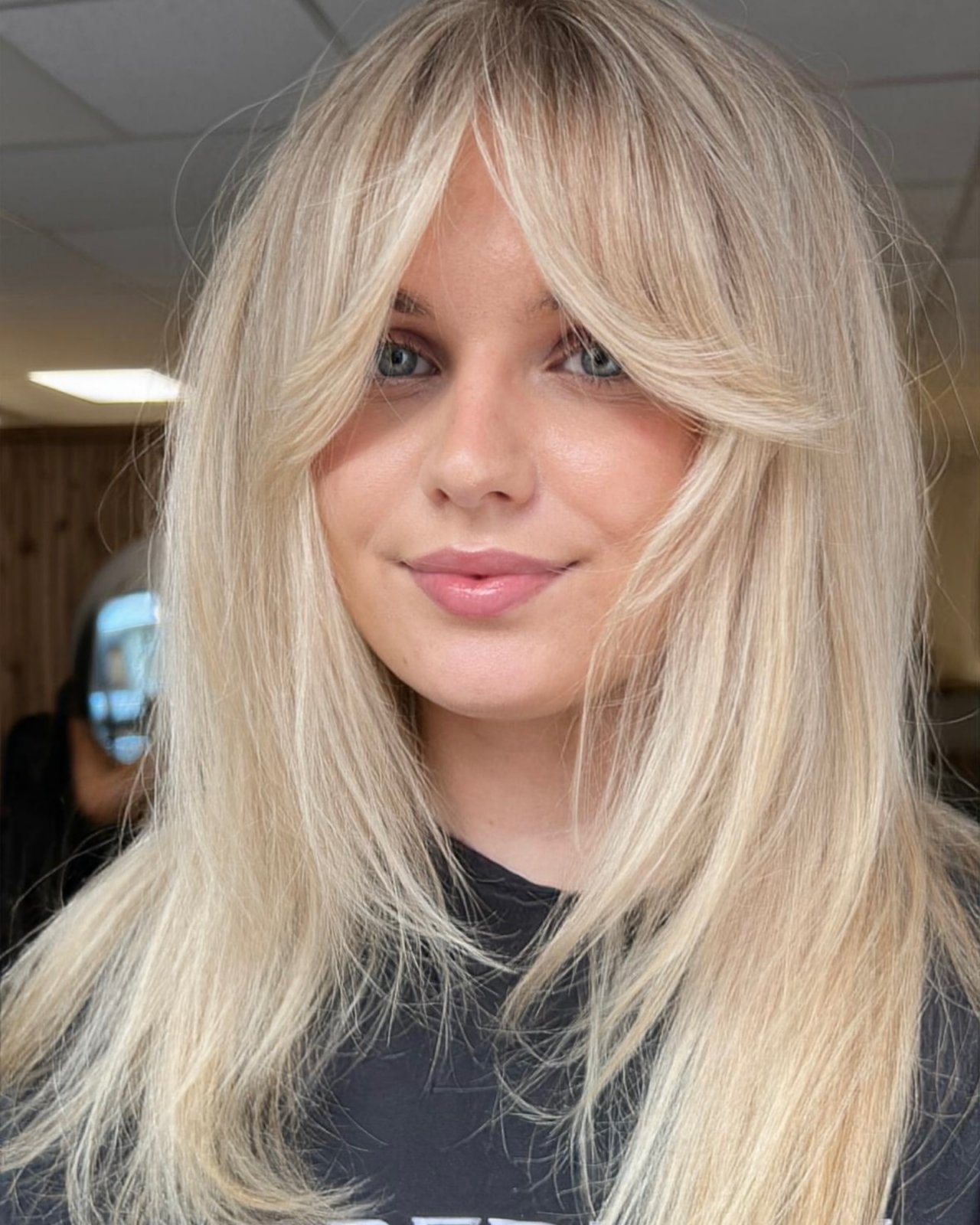 Zbliżenie na blondynkę w grzywce curtain bangs.