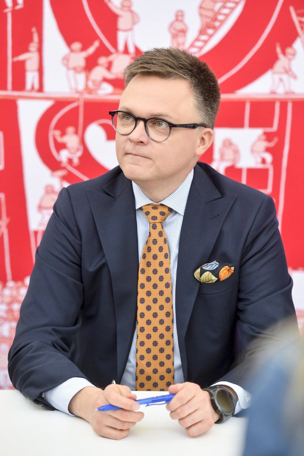 Szymon Hołownia w garniturze i pomarańczowym krawacie