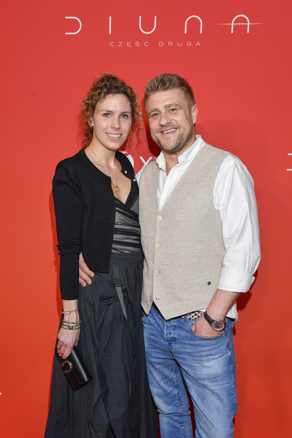 Tomasz Jakubiak w kamizelce obok żony w czarnej sukience
