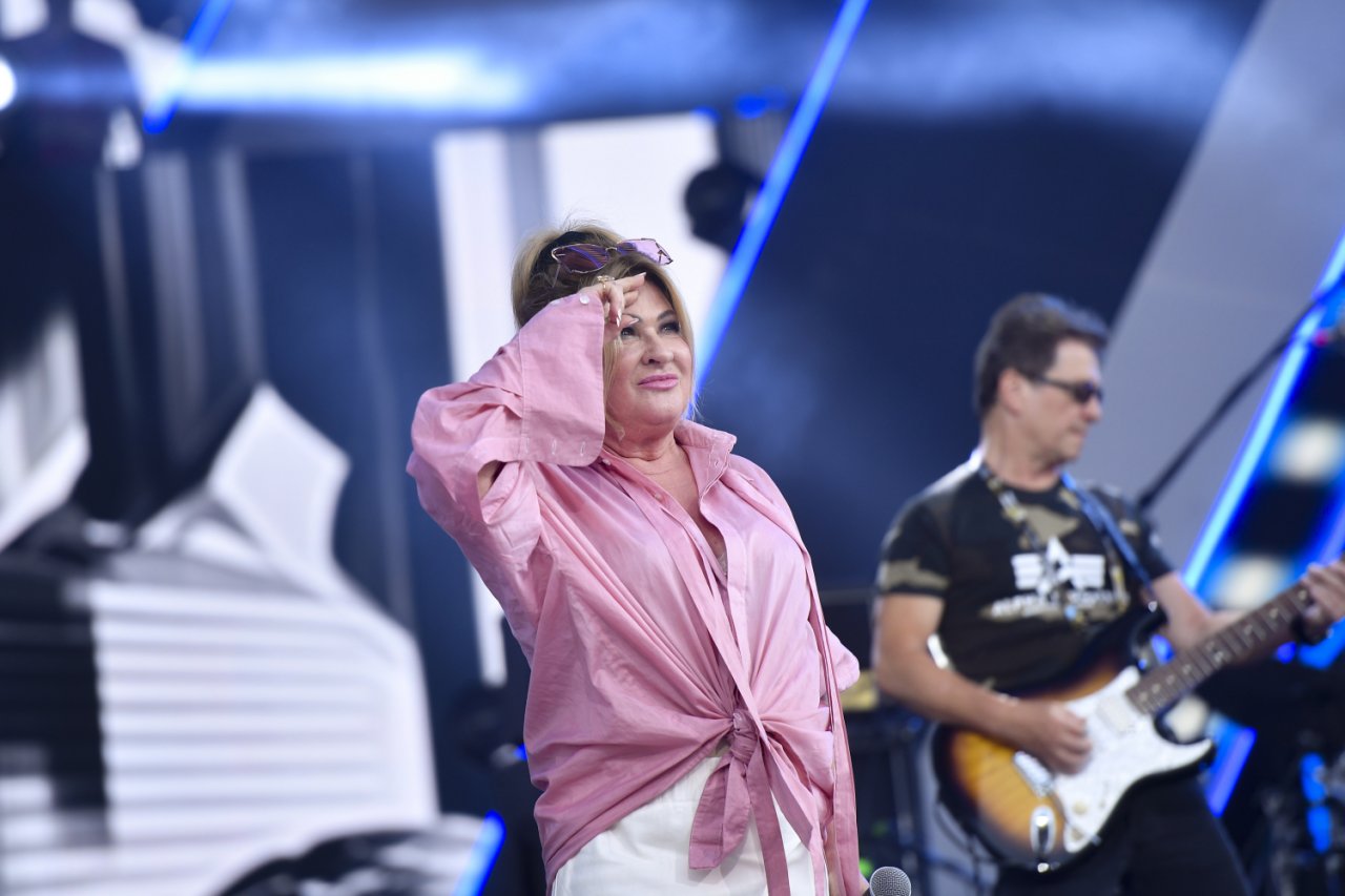 Beata Kozidrak w różowej bluzce i białych spodniach