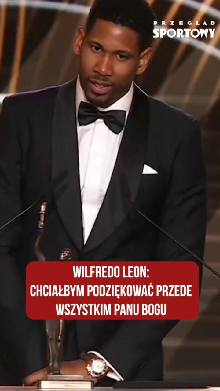Wilfredo Leon w garniturze z muszką stoi za mikrofonem