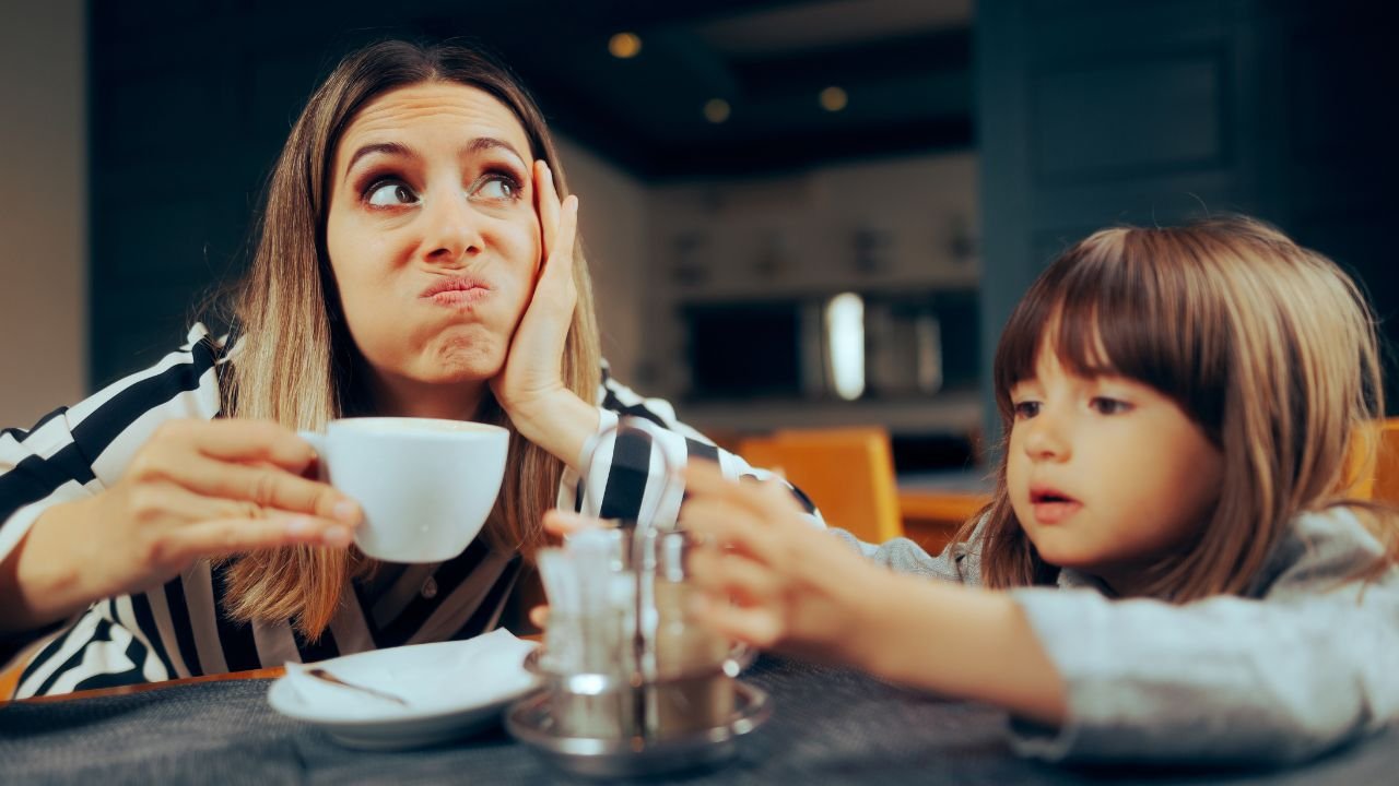 Znudzona kobieta matka pije kawę w restauracji przy stoliku z dzieckiem