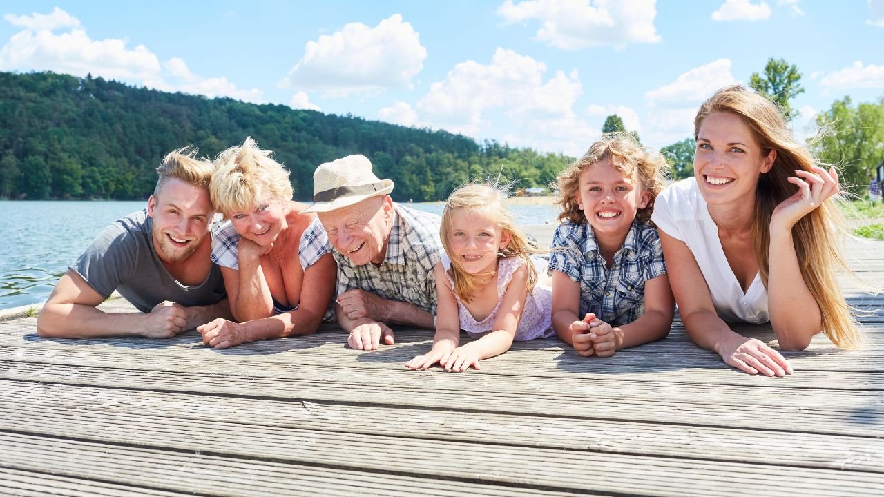 Dziadkowie z wnukami na wakacjach na pomoście nad wodą
