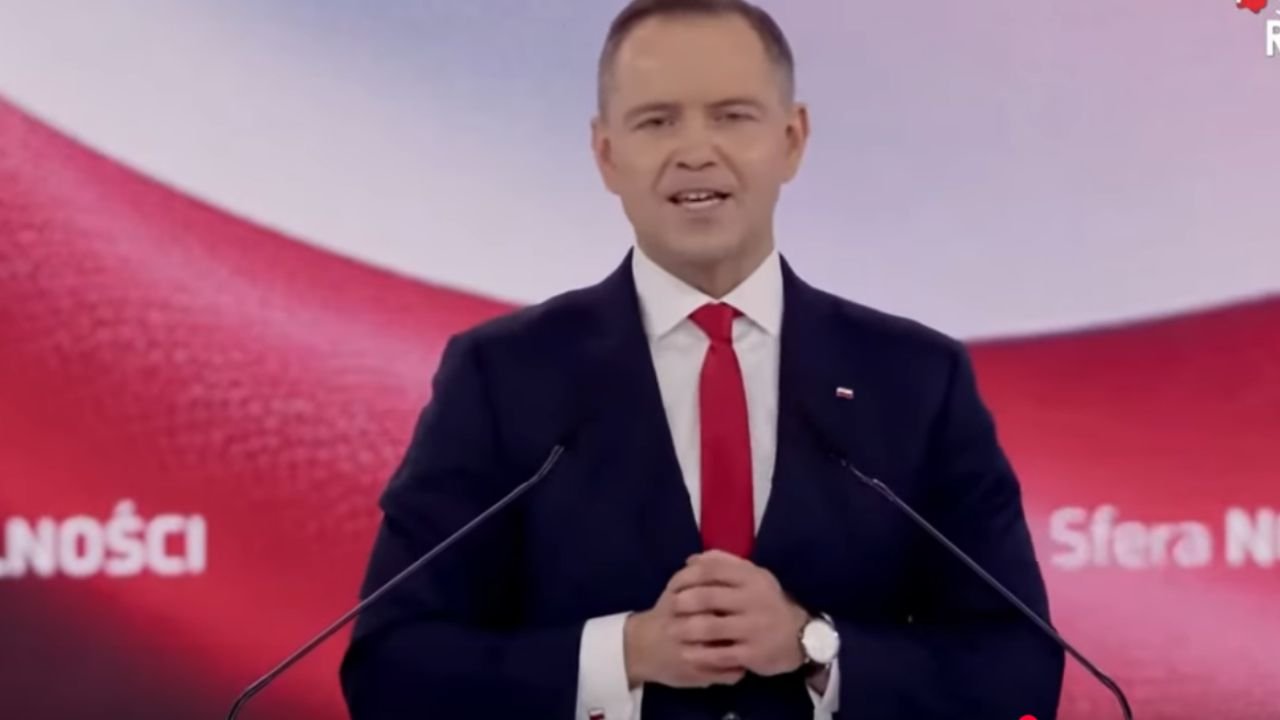 karol-nawrocki w garniturze na tle flagi