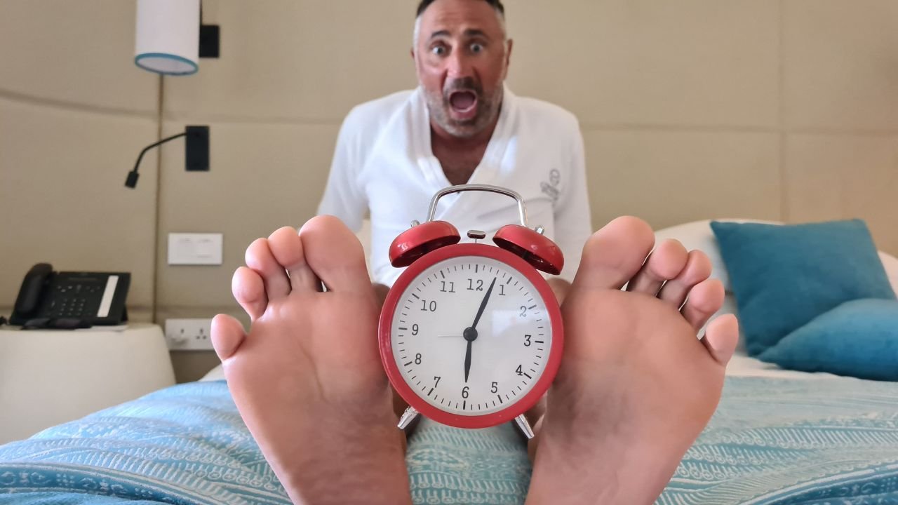 Przestraszony mężczyzna z budzikiem między stopami