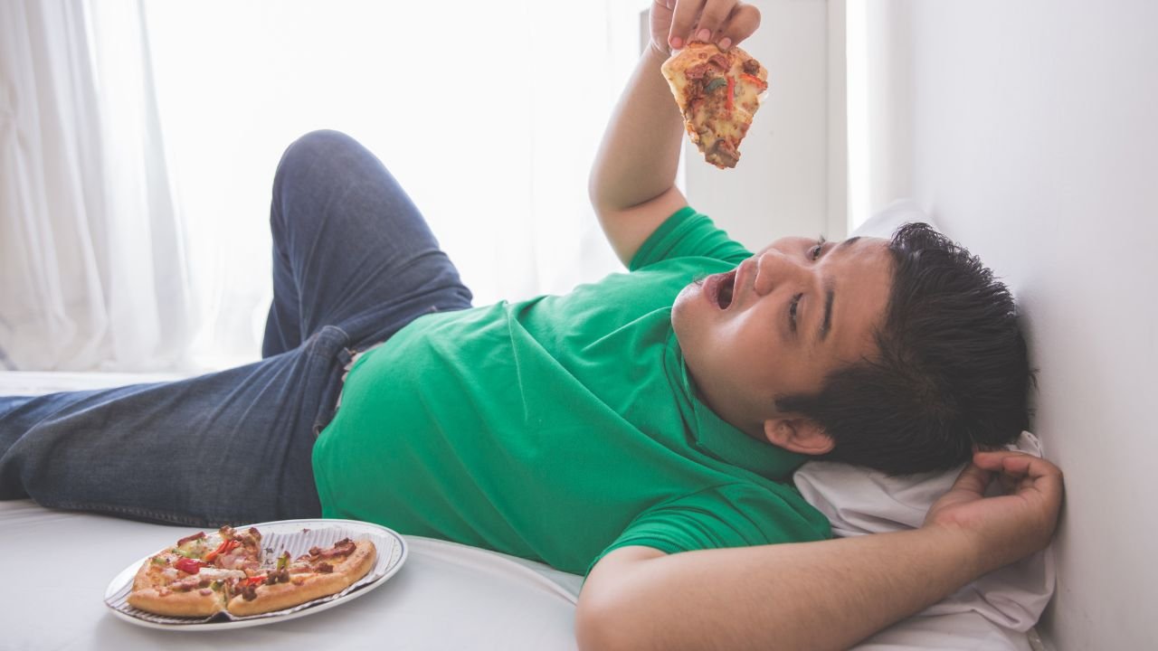 Leniwy mężczyzna je pizzę półleżąc