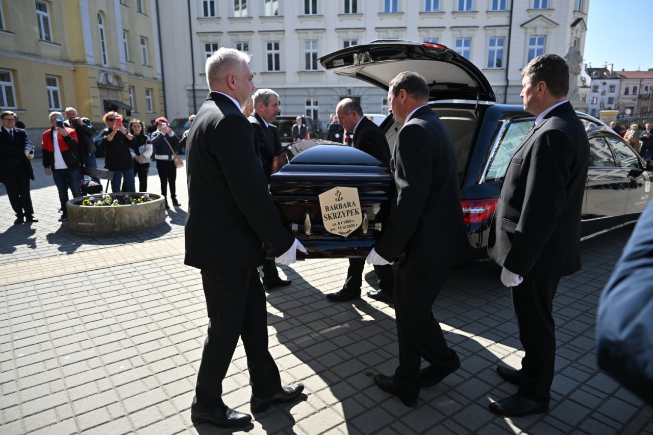 Pracownicy firmy pogrzebowej wkładają trumnę z ciałem Barbary Skrzypek do karawanu