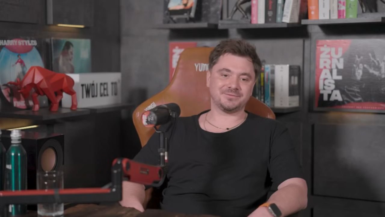 Daniel Martyniuk w czarnym t-shircie na brązowym fotelu u Żurnalisty