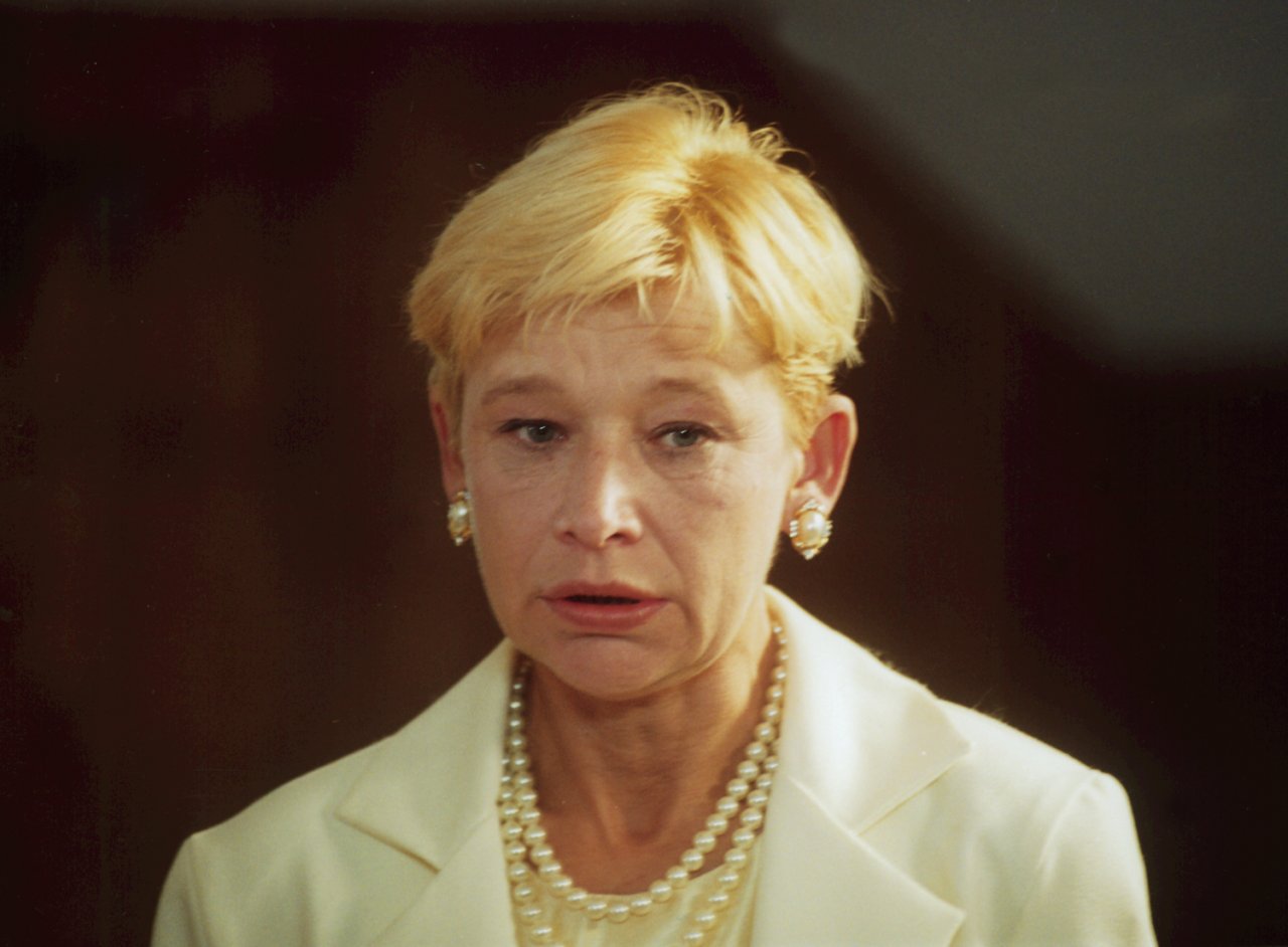 Jadwiga Jankowska-Cieślak w krótkich blond włosach, z klipsami i perłami- twarz i ramiona