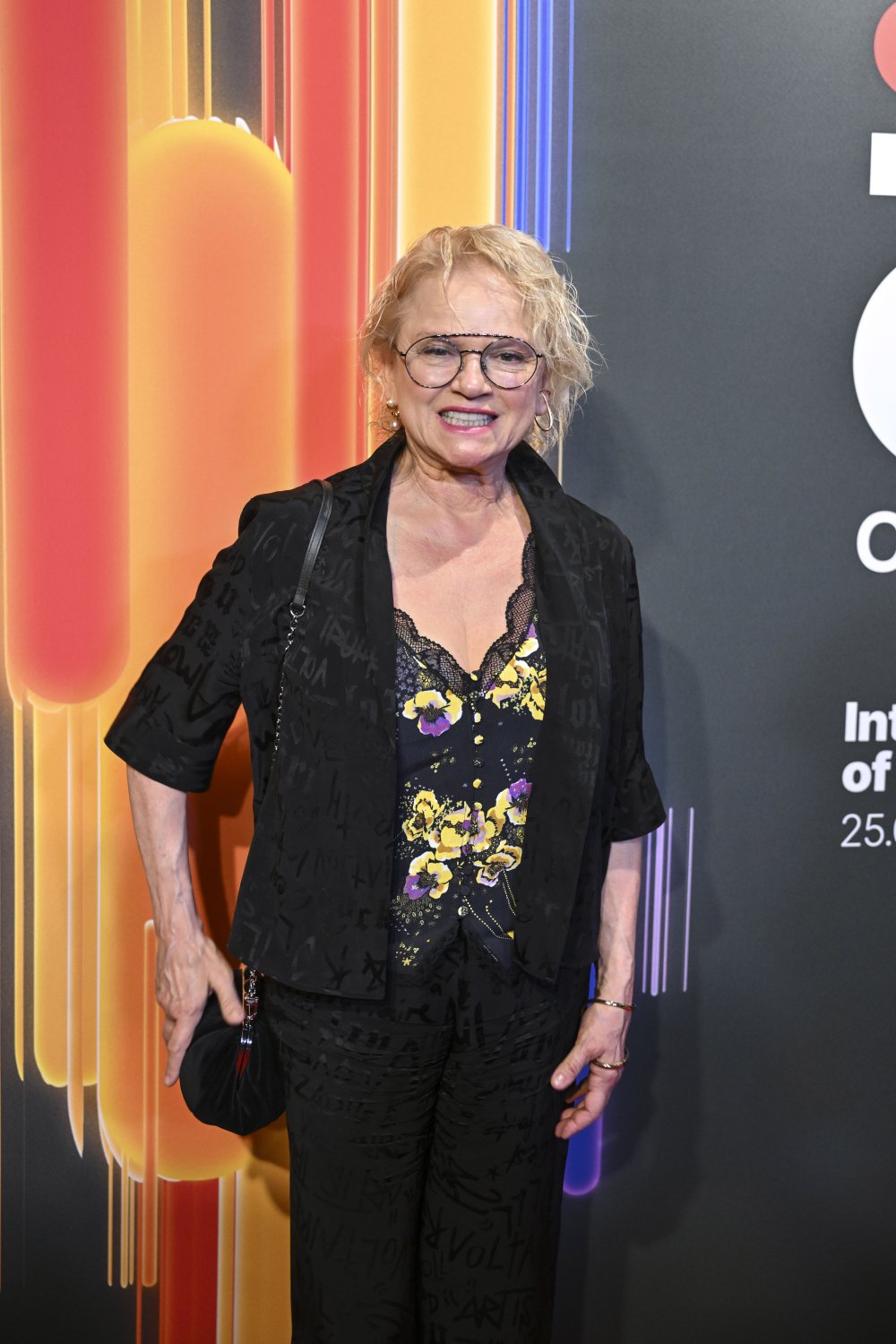 Katarzyna Figura w czarnym komplecie i kwiecistej bluzce