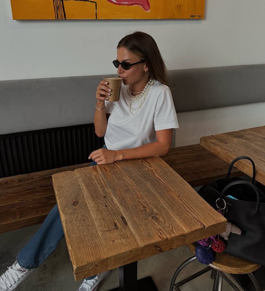 Anna Lewandowska pije kawę za drewnianym stolikiem