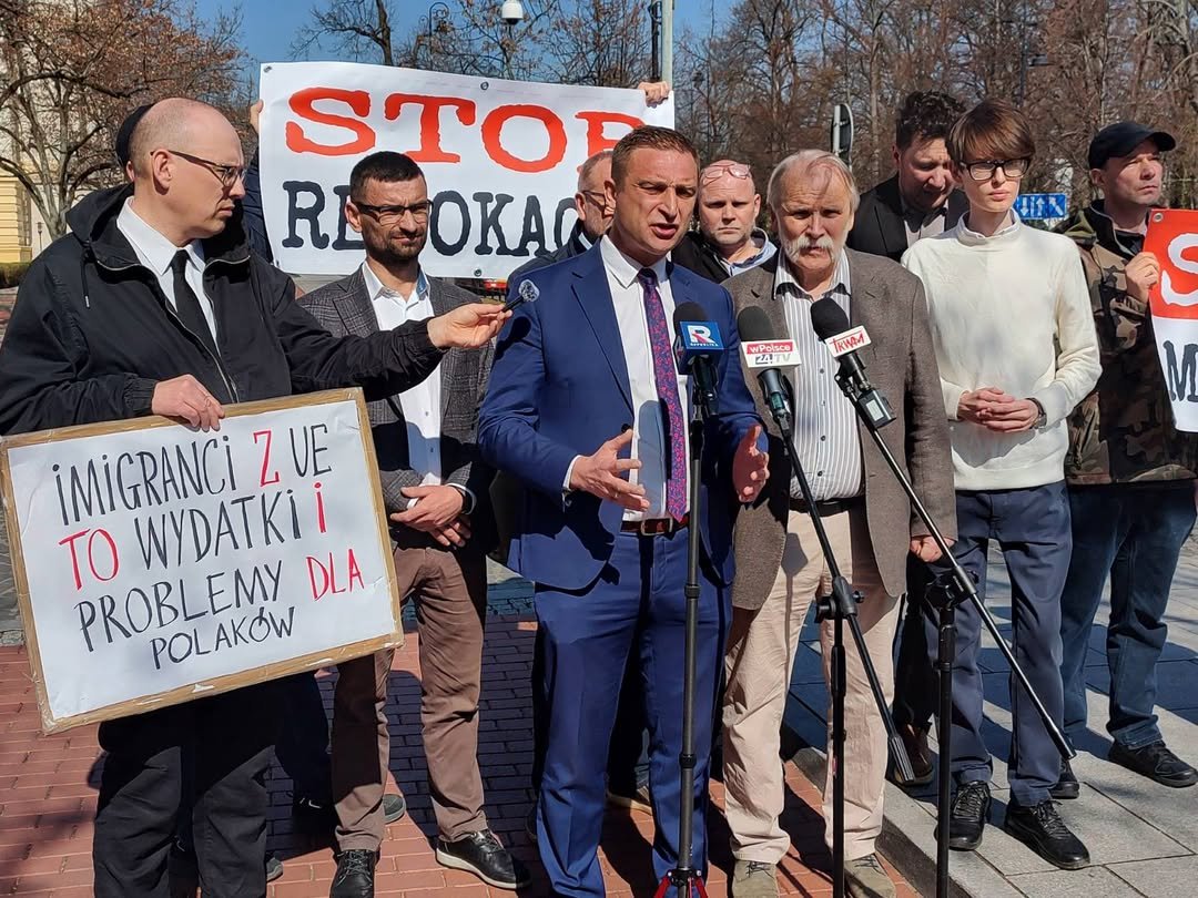 Robert Bąkiewicz w niebieskim garniturze na spotkaniu publicznym przeciwko imigrantom