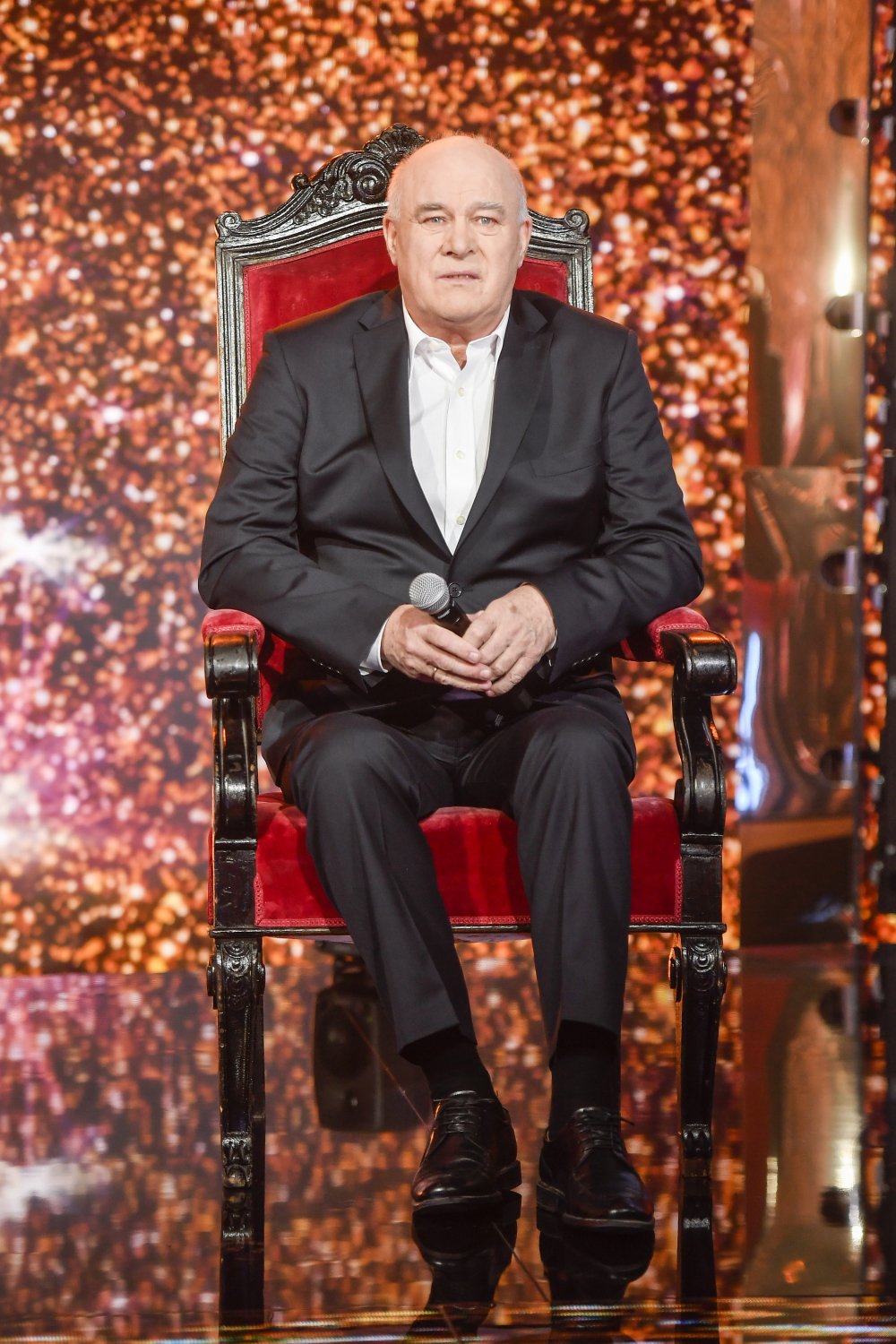 Ryszard Rynkowski w garniturze siedzi na zdobnym krześle