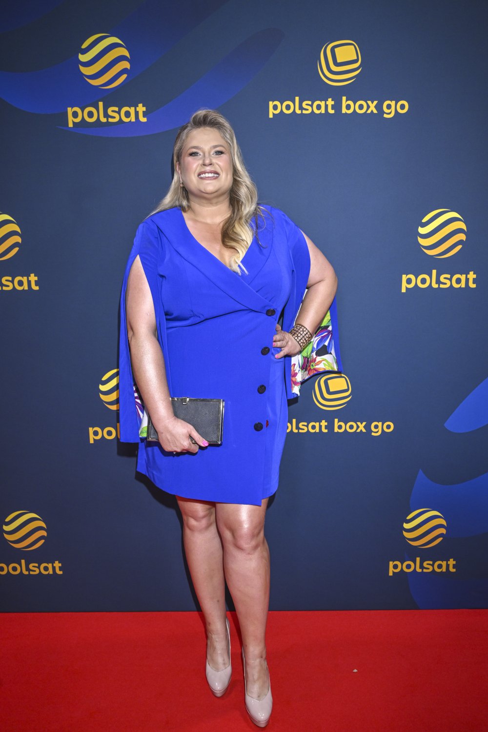 Ela Romanowska w chabrowej sukience i z czarną torebką w dłoni na ściance Polsatu