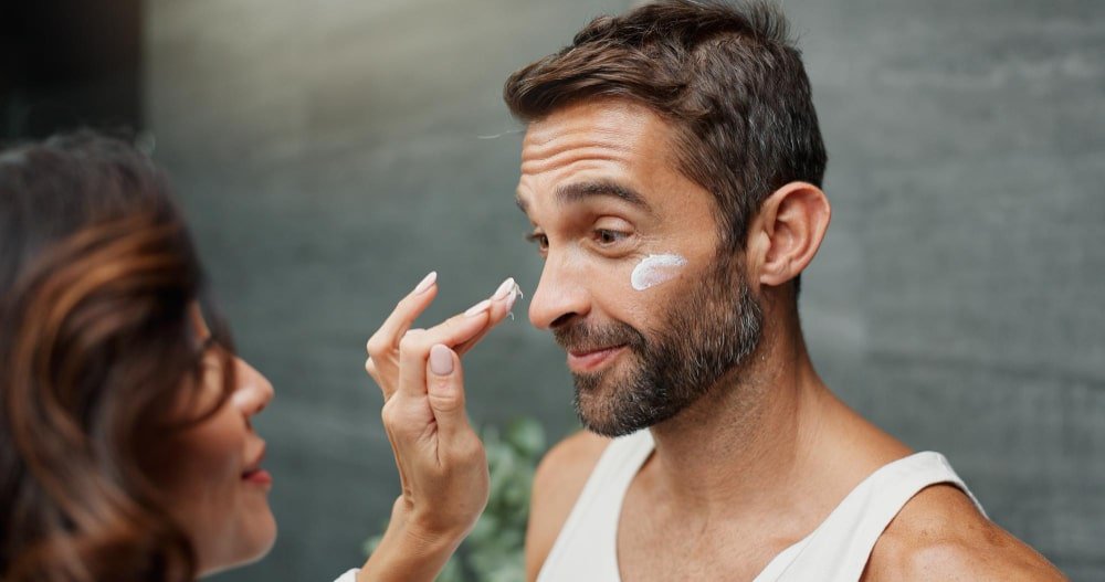 Mężczyzna nakładający na policzek krem dla mężczyzn