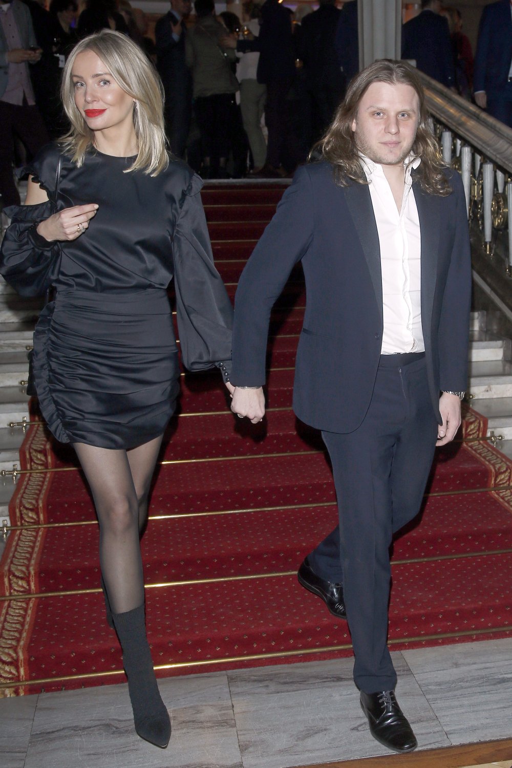 Agnieszka Woźniak-Starak i Piotr Woźniak-Starakw eleganckich strojach ida po schodach