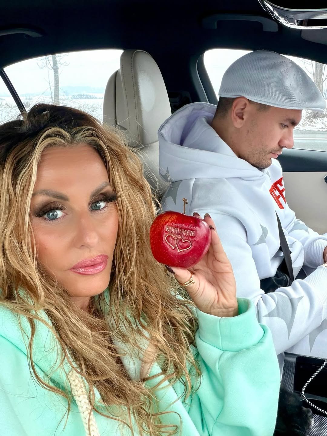 Dagmara Kaźmierska z jabłkiem w ręku, siedzi w aucie z synem Conanem