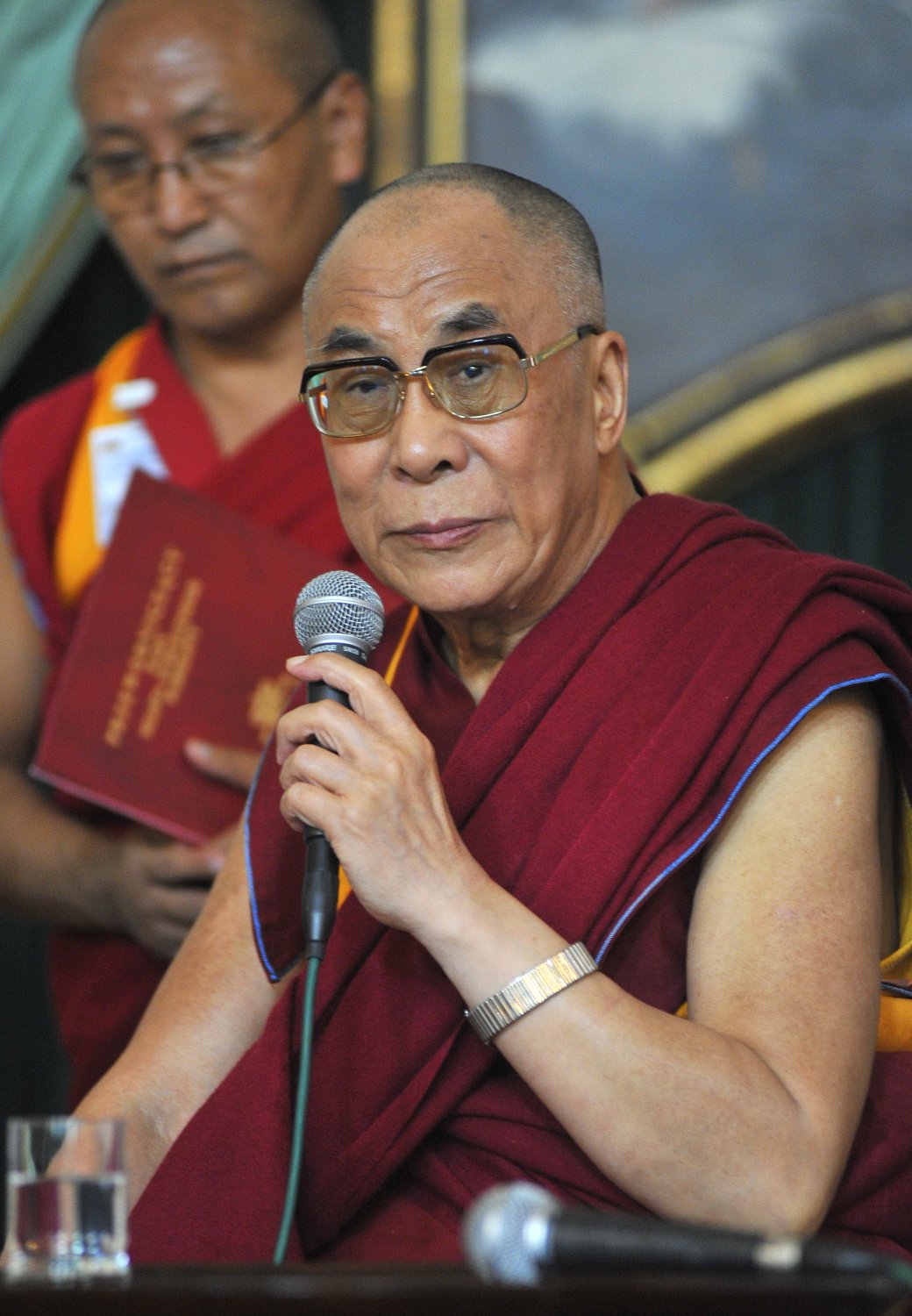 Dalajlama w czerwonej szacie trzyma mikrofon