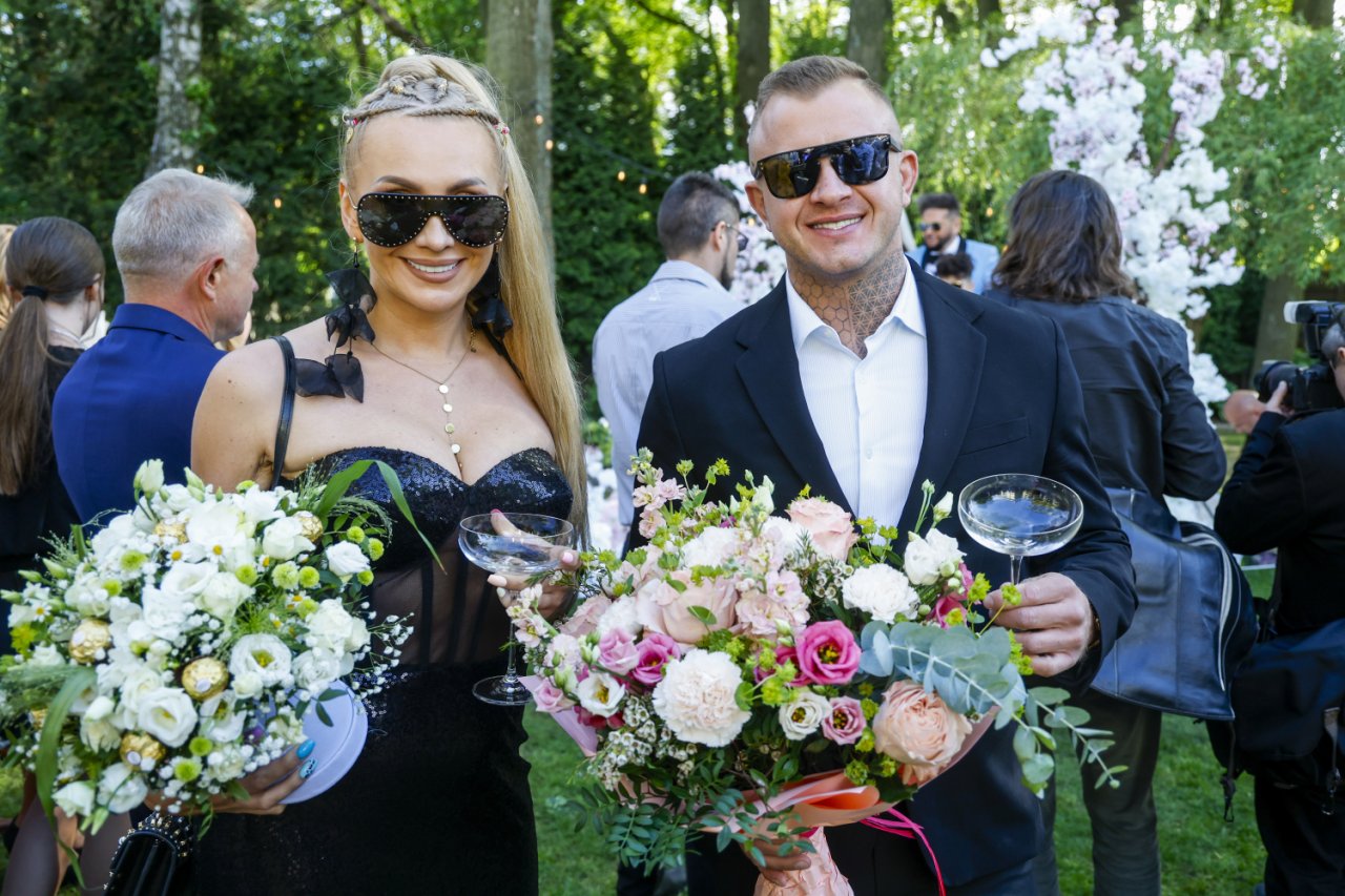 Joanna Narożna i Dawid Narożny w eleganckich strojach z bukietem kwiatów