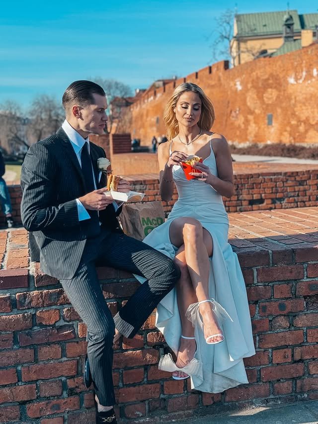 Hanna Żudziewicz i Jacek Jeschke siedzą na murku w strojach ślubnych