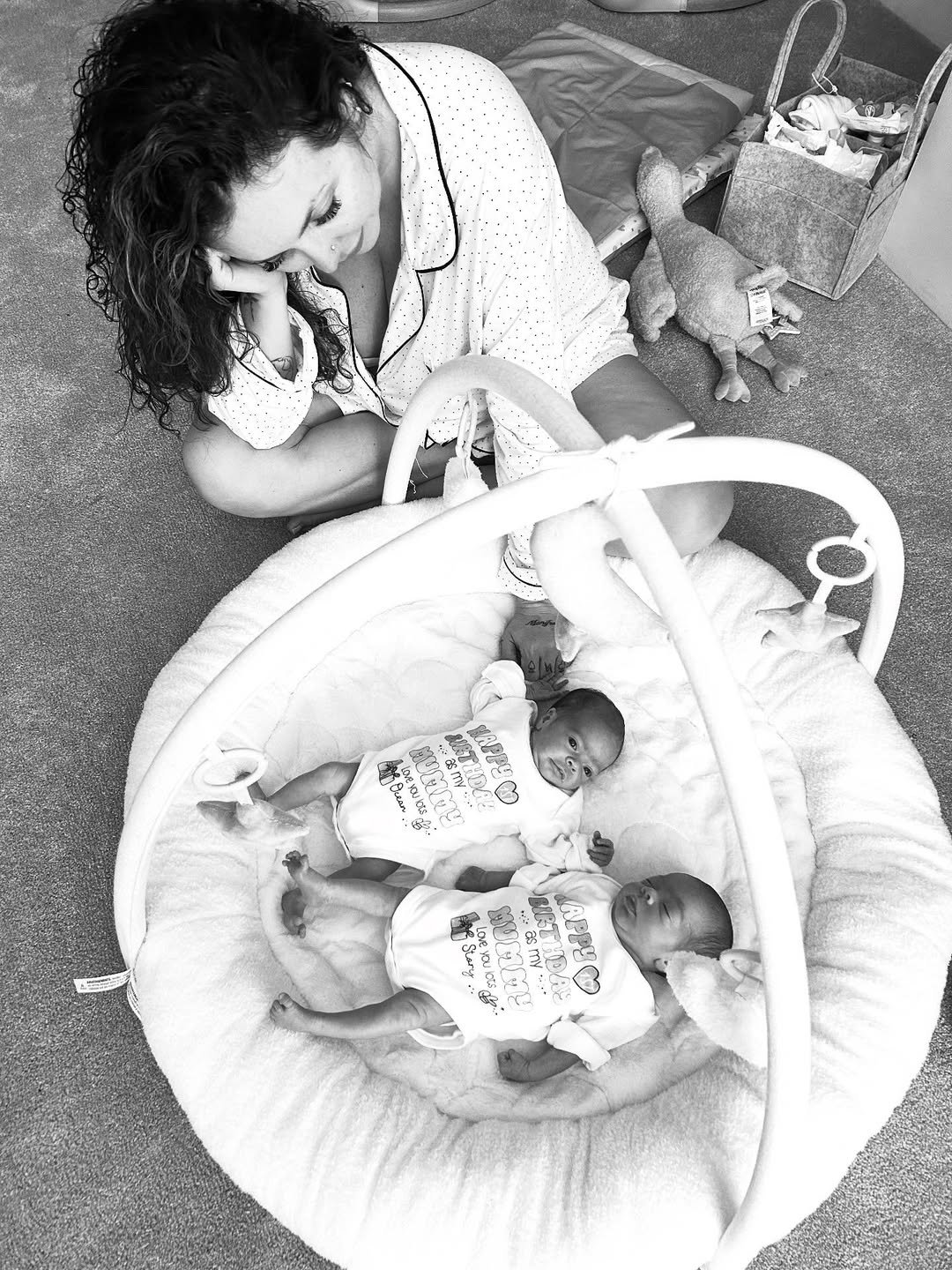 Czarno-białe zdjęcie Jesy Nelson pochylonej nad córeczkami