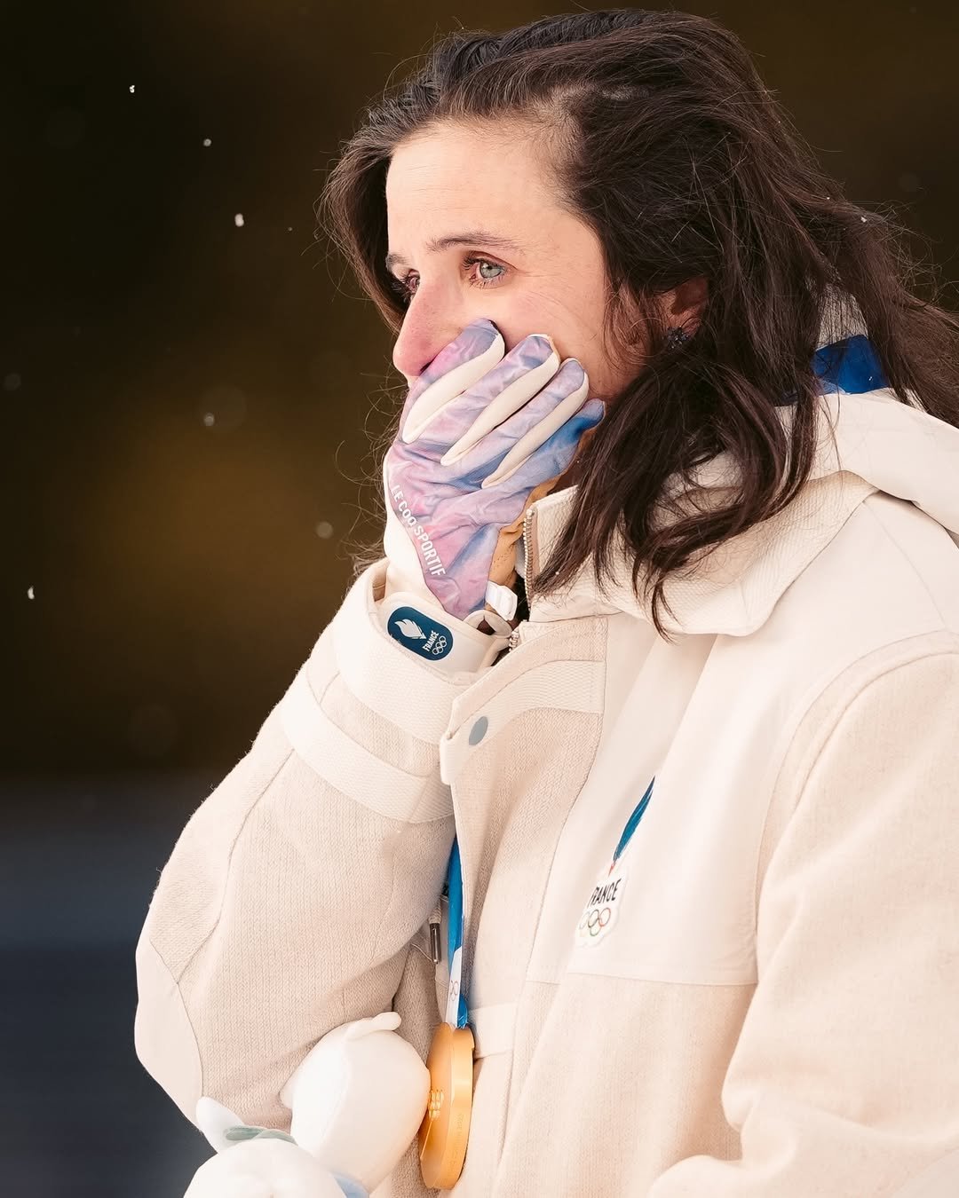 Julia Simon w białej kurtce zimowej przykłada dłoń do ust