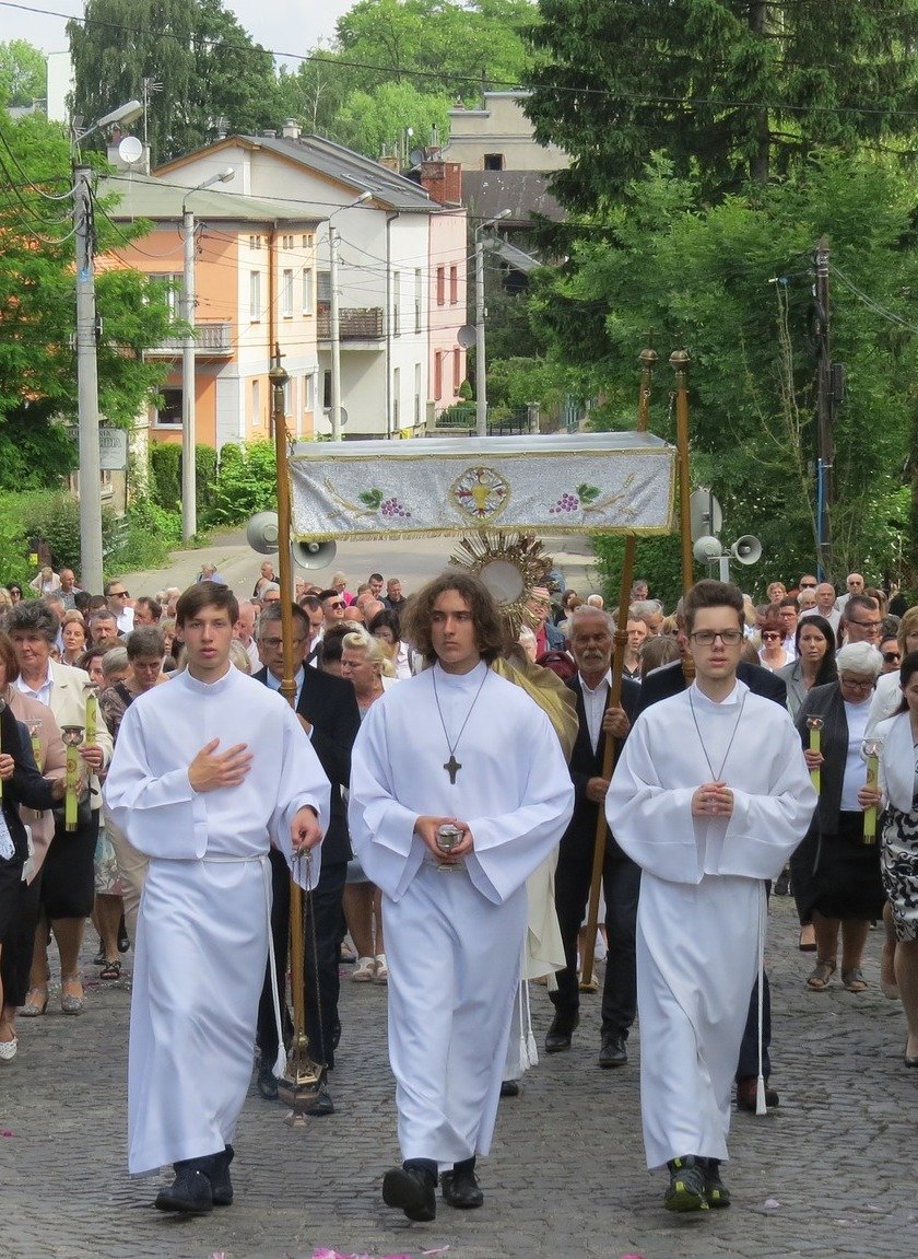 Kacper Tomasiak w komży idzie drogą z ministrantami