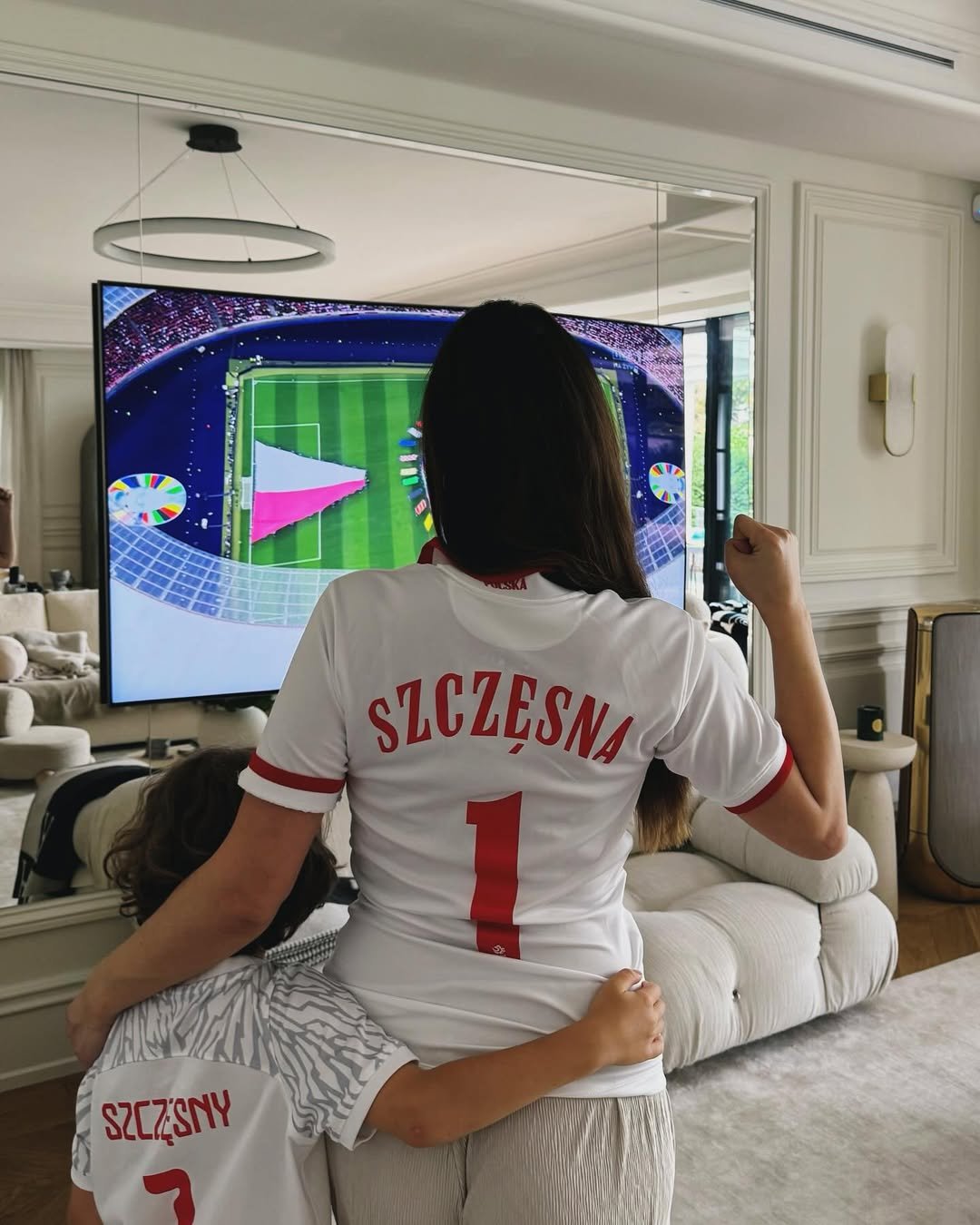 Marina Łuczenko szczęsna i liam szczęsny w koszulkach reprezentacji polski oglądają mecz na telewizorze