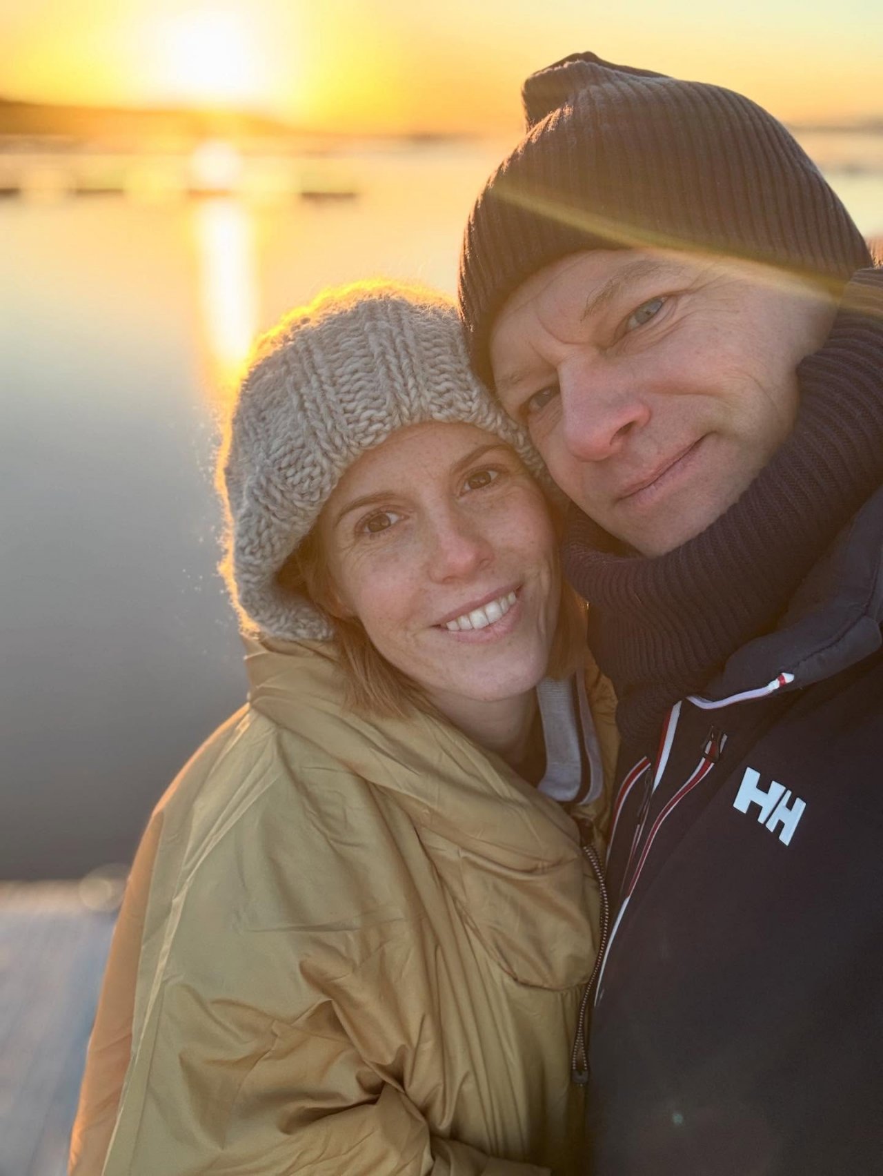 Maciej Stuhr i Katarzyna Stuhr w zimowych czapkach na tle zachodzącego słońca