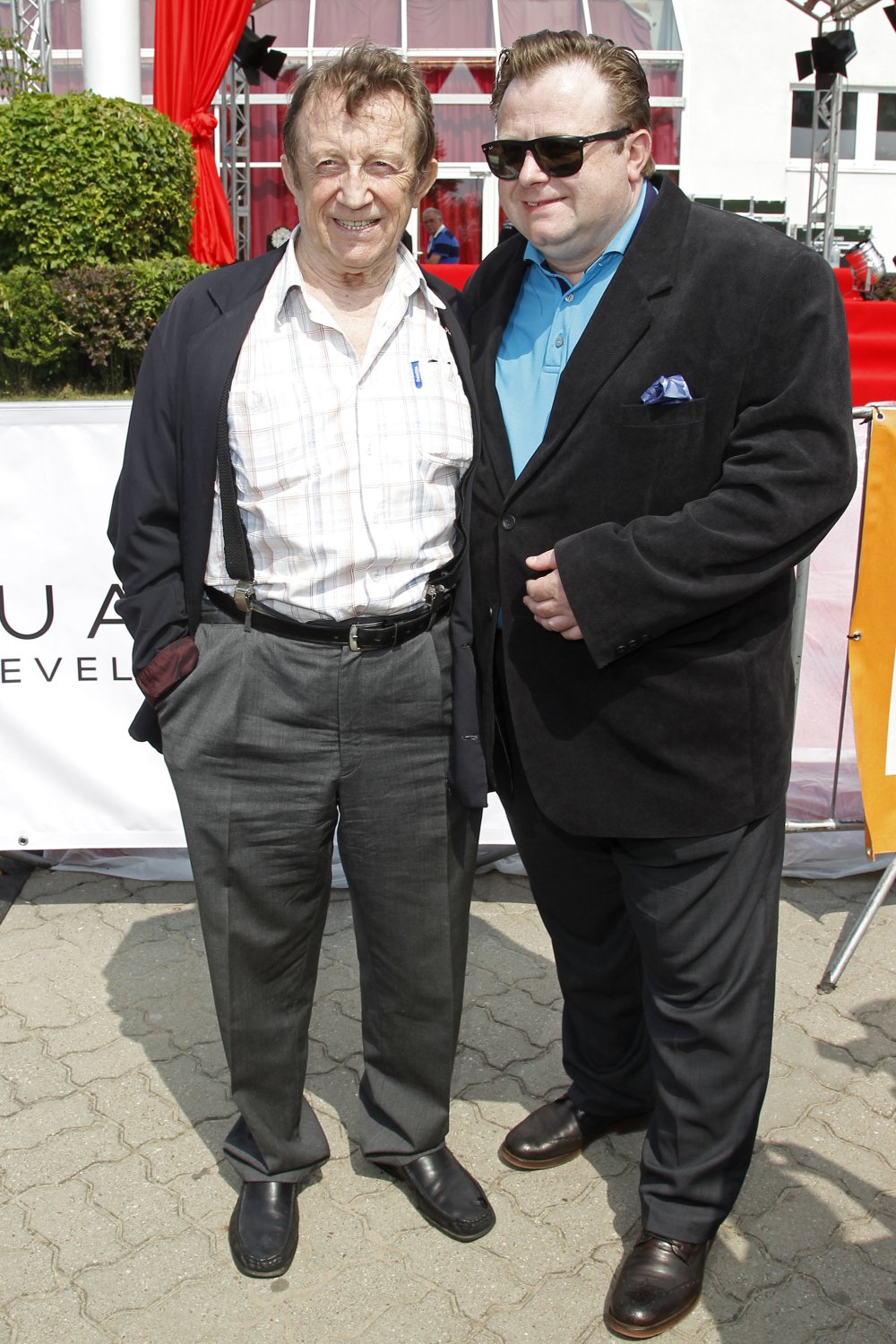 Olaf Lubaszenko i Edward Linde-Lubaszenko w koszulach i marynarkach pozują na tle cegły