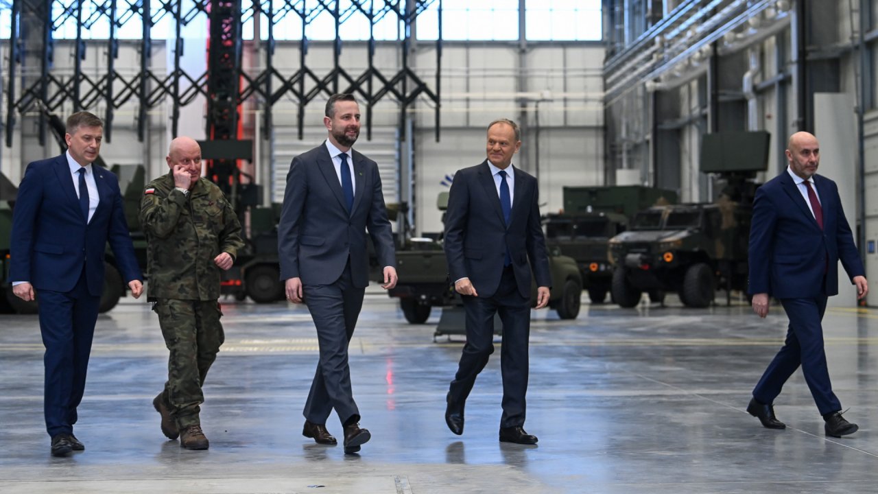 Ubrani w garnitury Władysław Kosiniak-Kamysz i Donald Tusk idą w towarzystwie innych mężczyzn