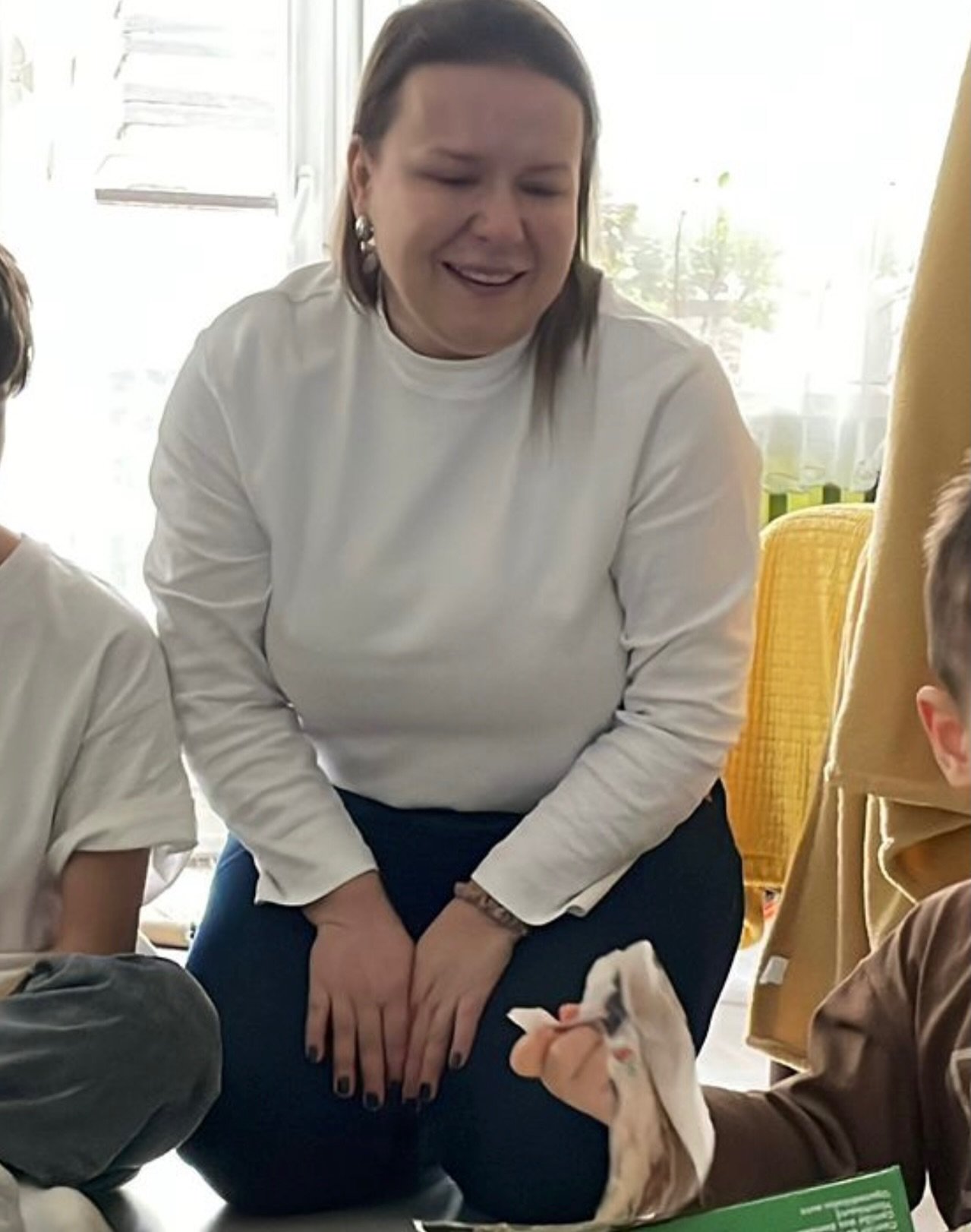 Aneta Zając w białej bluzce i czarnych spodniach siedzi na podłodze