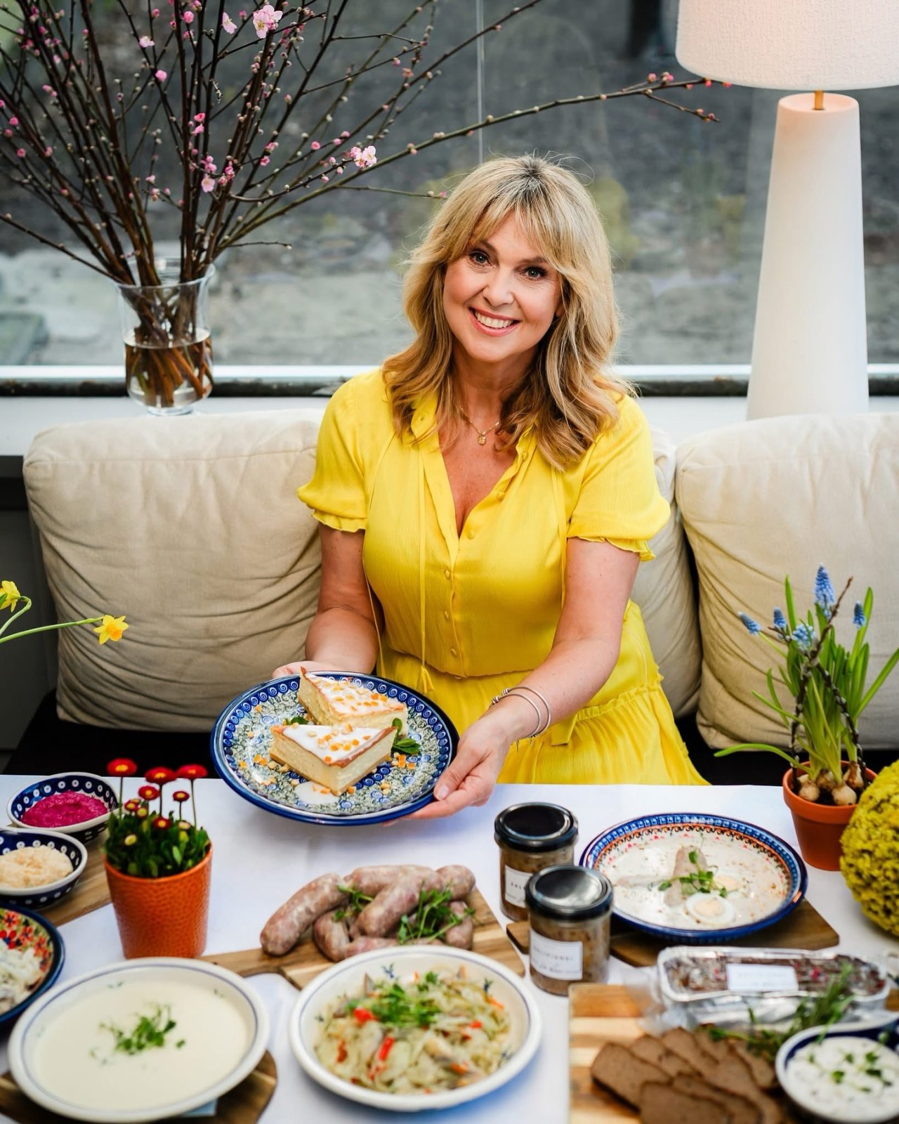 Ewa Wachowicz w żółtej sukience przy stole