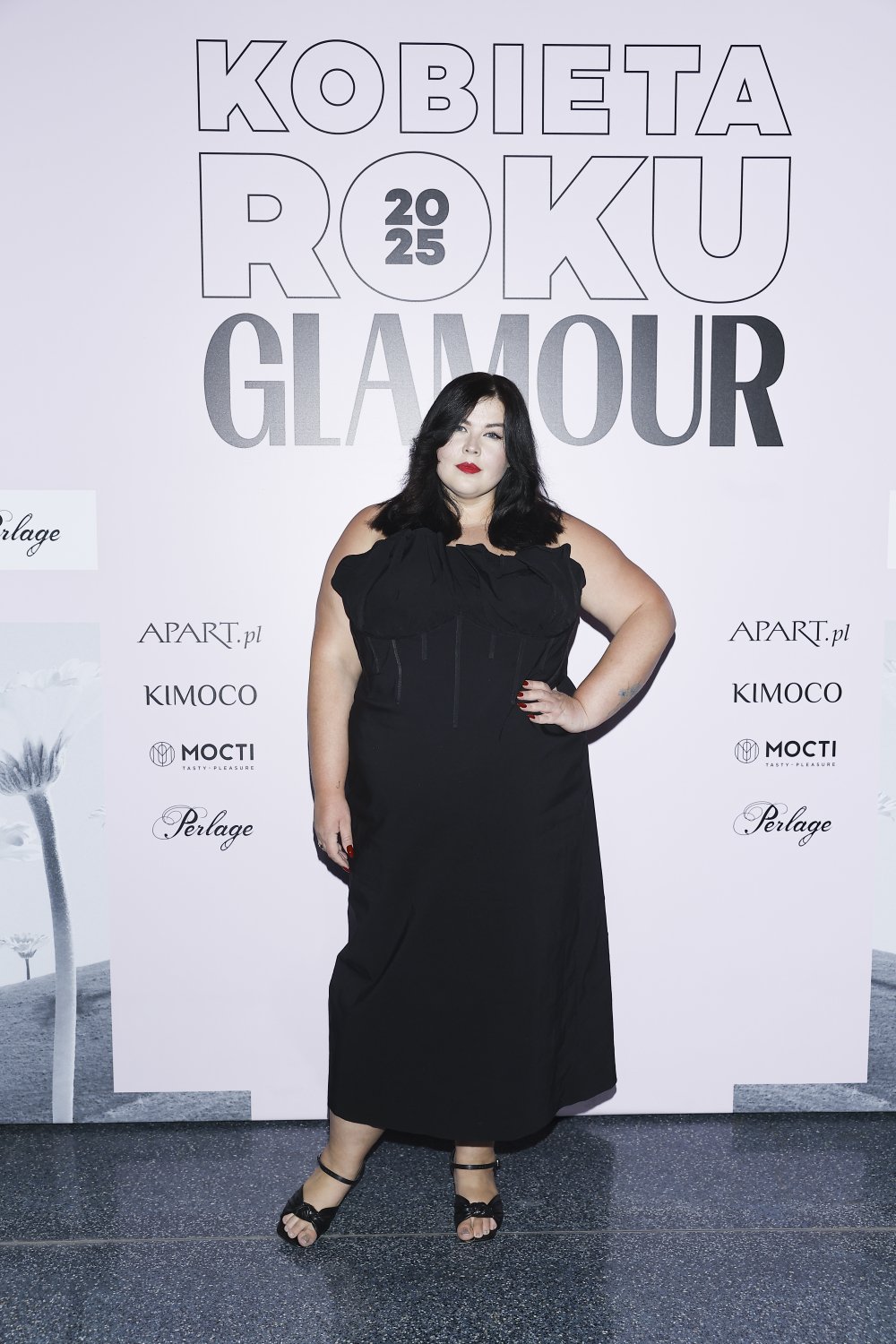 Ewa Zakrzewska w czarnej sukni na ściance z napisecm KOBIETA ROKU GLAMOUR