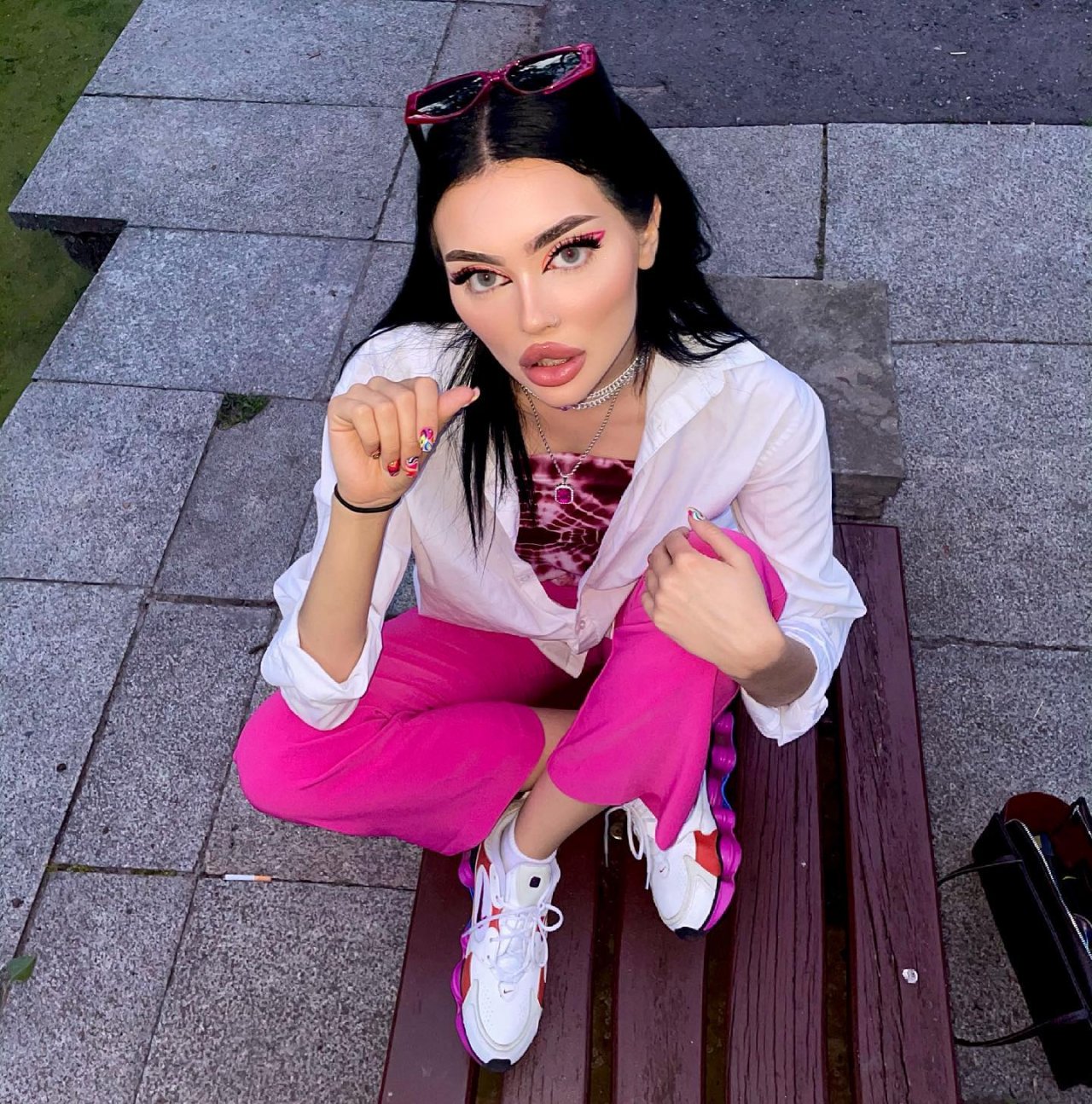 Masza Graczykowska w kolorowych ubraniach siedzi na ławce