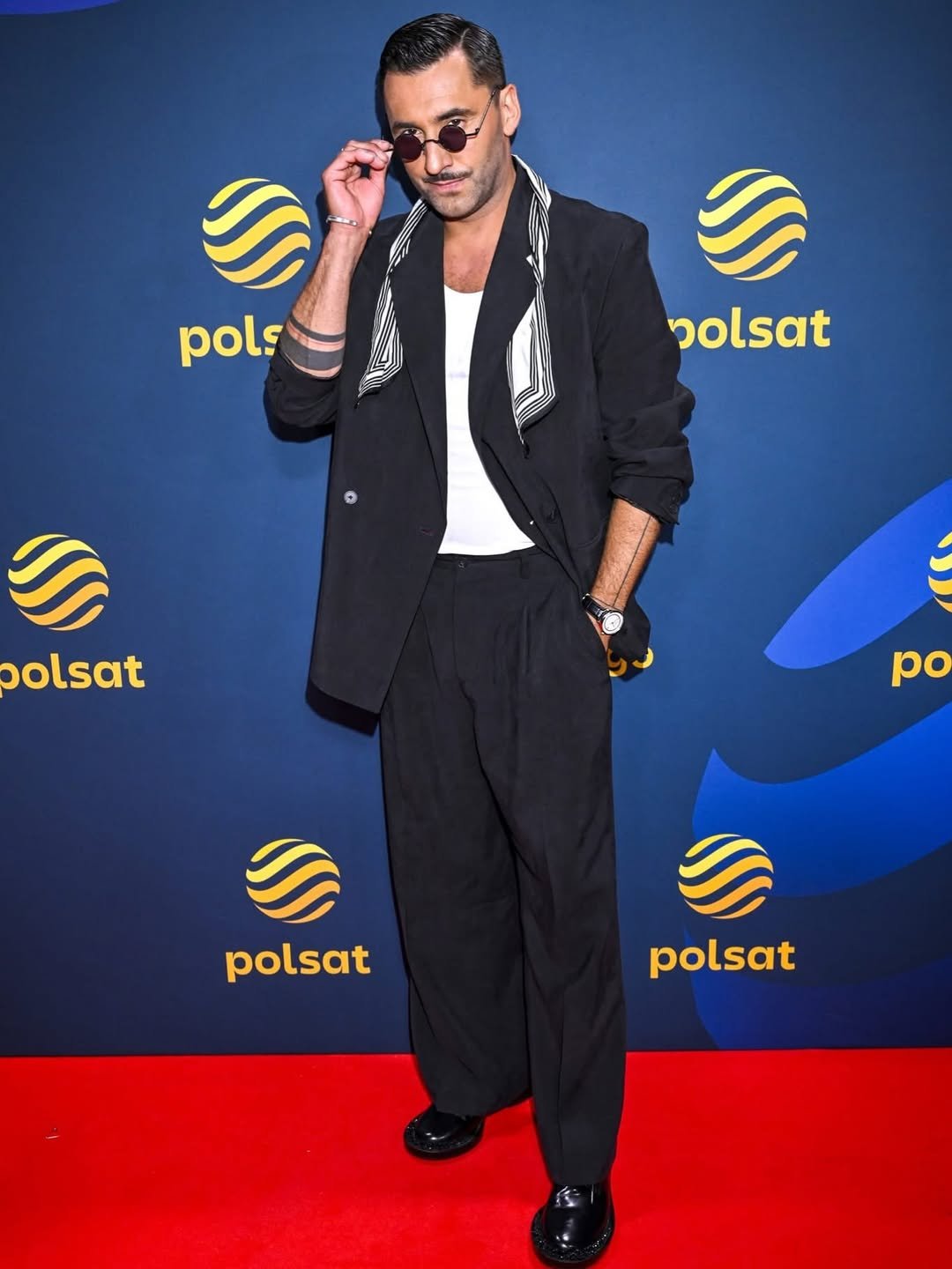 Rafał Maserak w ciemnym garniturze na ściance