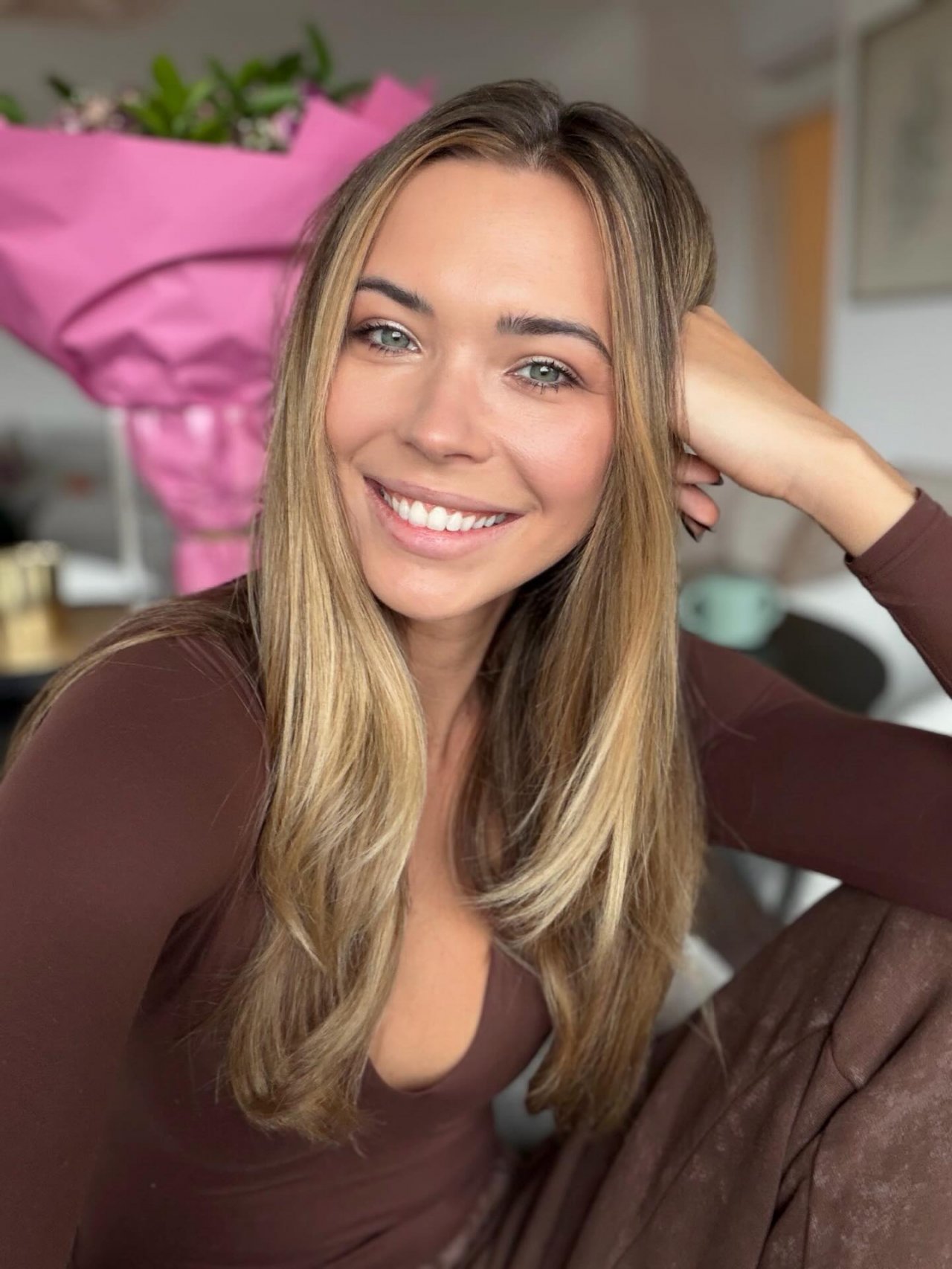 roześmiana Sandra Kubicka pozuje na tle pieknego bukietu kwiatów