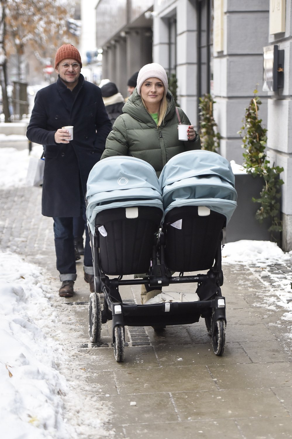 Bartłomiej Topa z żoną prowadzą bliźniaczy wózek w zimowej miejskiej scenerii