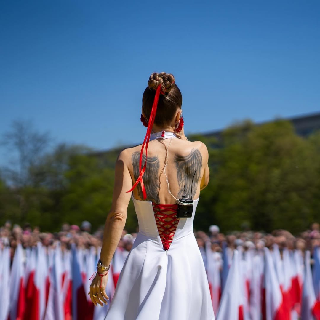 doda w biało czerwonej pelerynie śpiewa hymna polski - święto flagi, błonia kraków