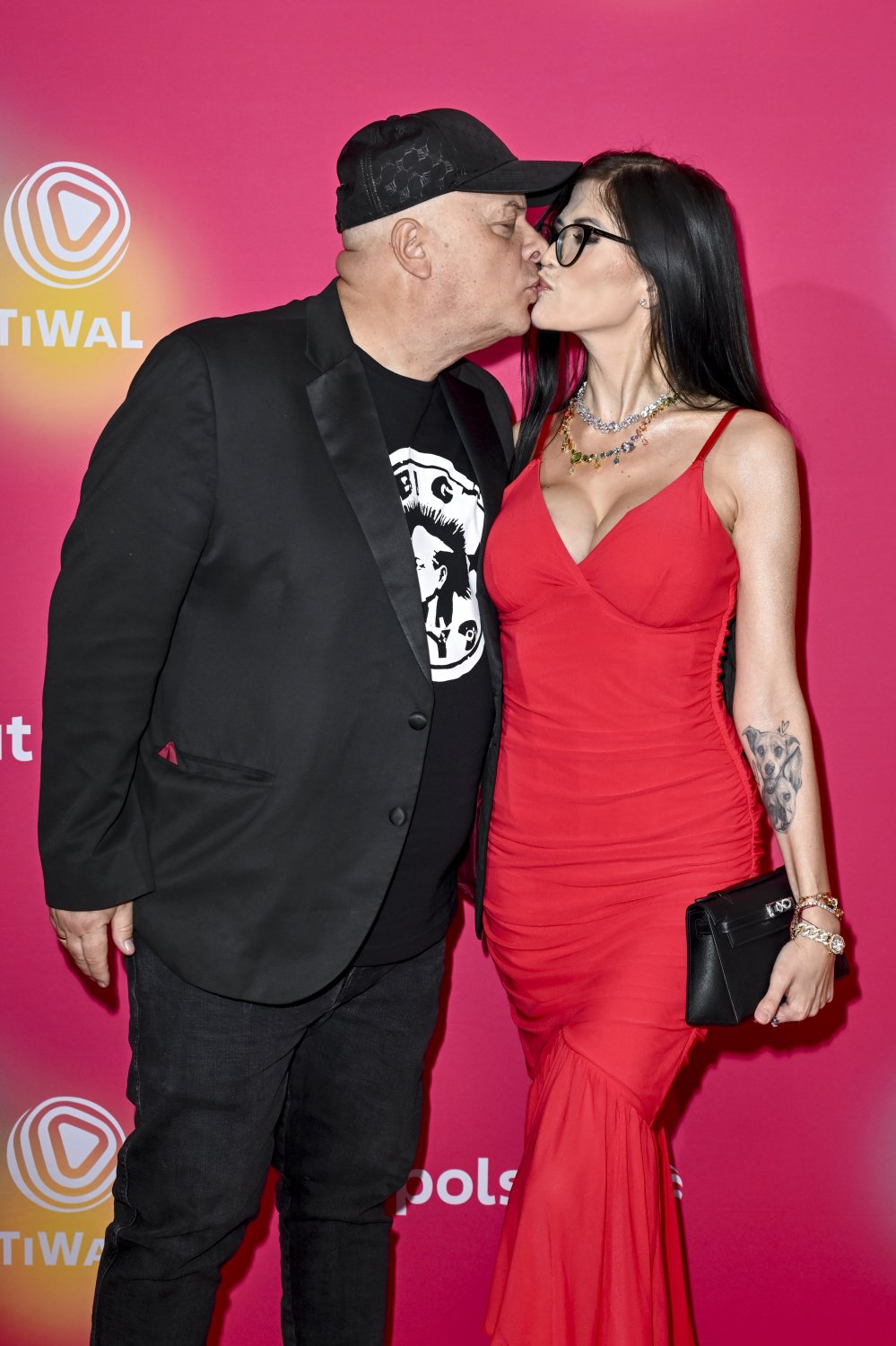 Krzysztof i Karolina Skibowienie szczędzą sobie czułości na ściance Sopot Festiwal, Karolina obrana w czerwoną suknię z dużym dekoltem, Krzysztof w czarnym garniturze, koszulke i czapkę z daszkiem